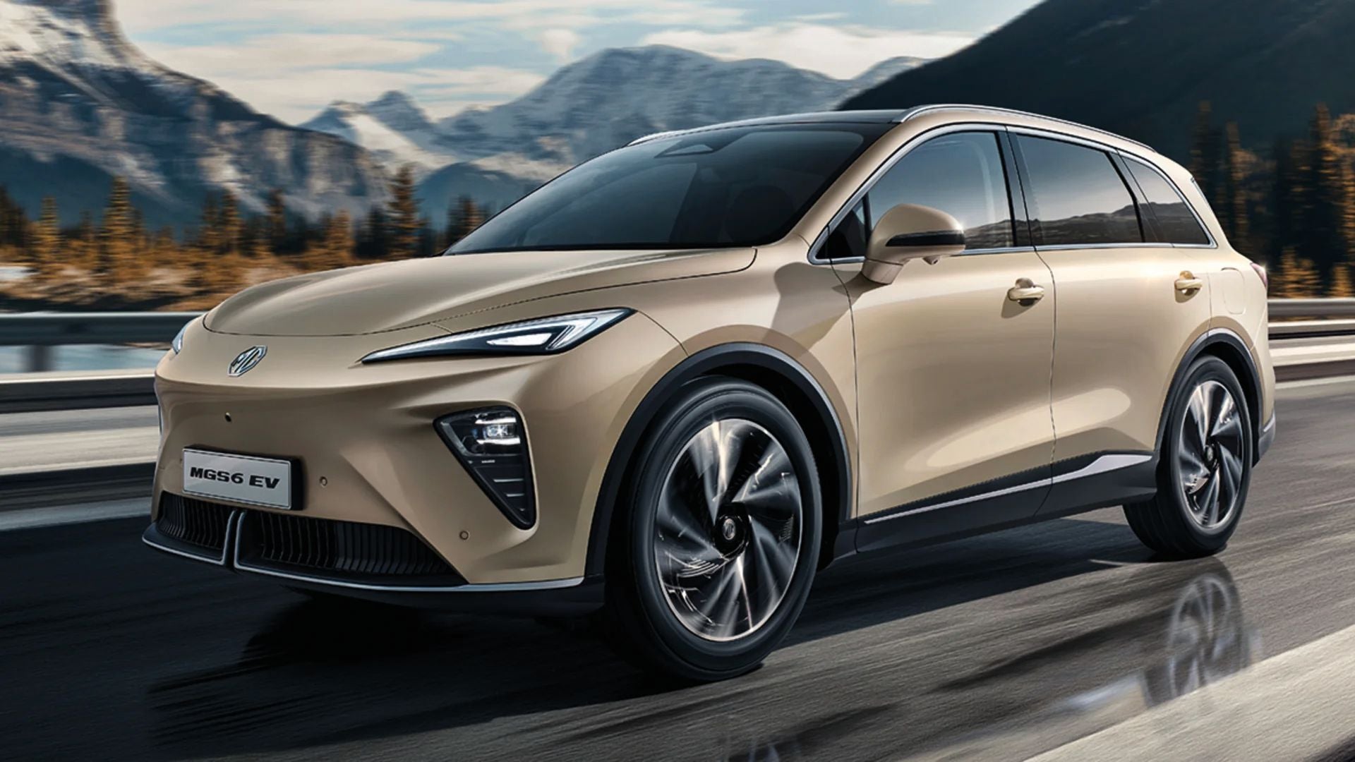 Beiger Elektro-SUV BYD MGS6 EV fährt auf einer Straße vor bergiger Landschaft.