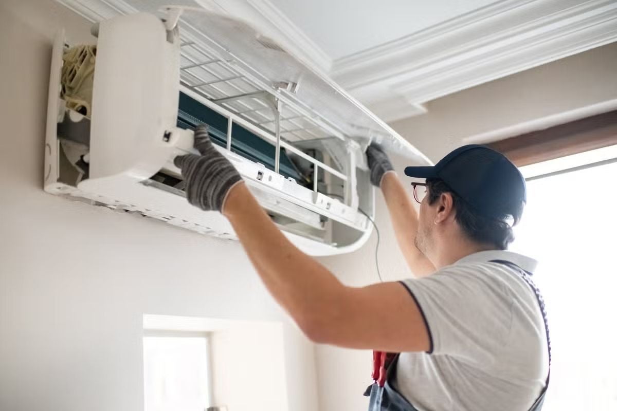 Techniker wartet eine Klimaanlage an der Wand in einem Raum.