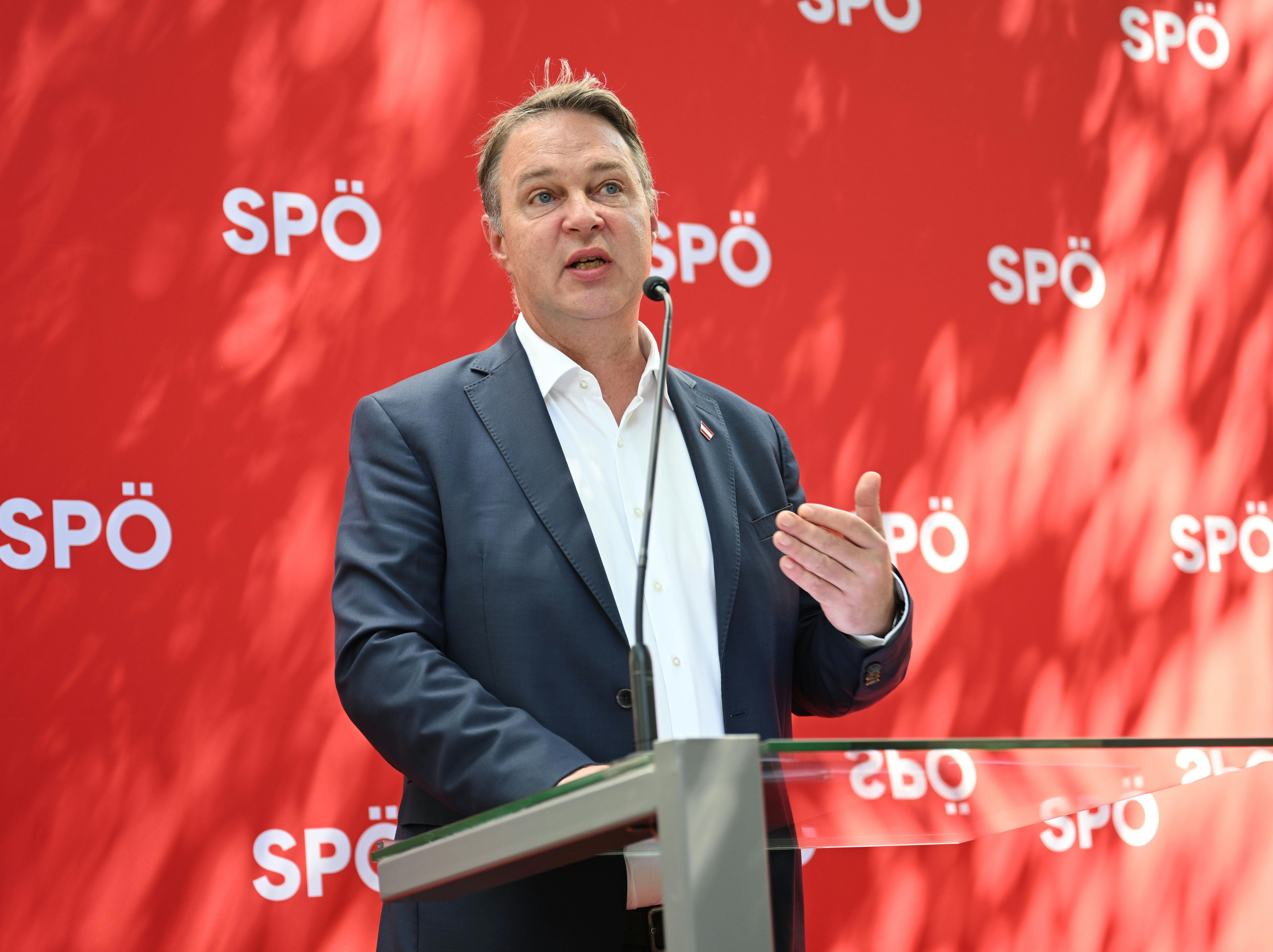Ein Mann im Anzug spricht bei einer Pressekonferenz vor rotem SPÖ-Hintergrund am Rednerpult.
