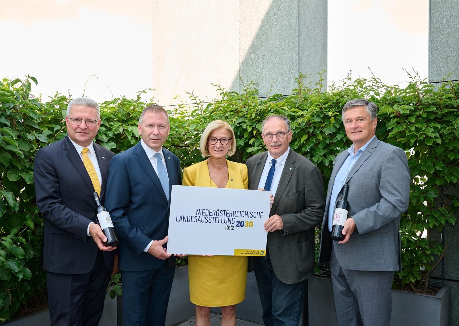 Posieren mit Weinflaschen und einem Schild zur Landesausstellung Retz 2030.