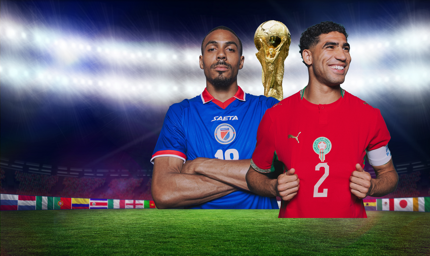 Zwei Fußballspieler aus Marokko und Haiti stehen vor einem Pokal im Stadion.