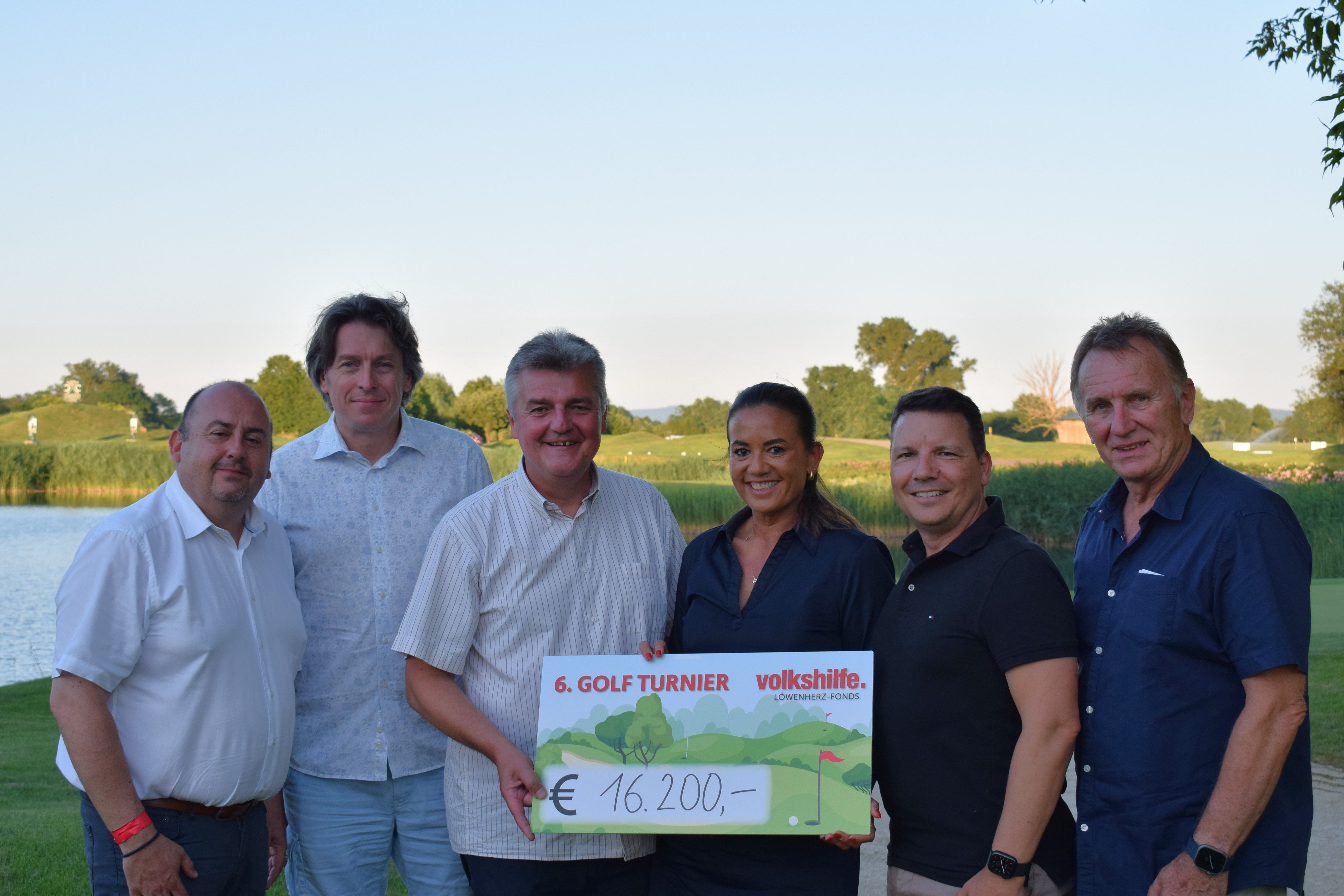 Sechs Personen halten einen großen Spendenscheck über 16.200 Euro bei einem Golfturnier.