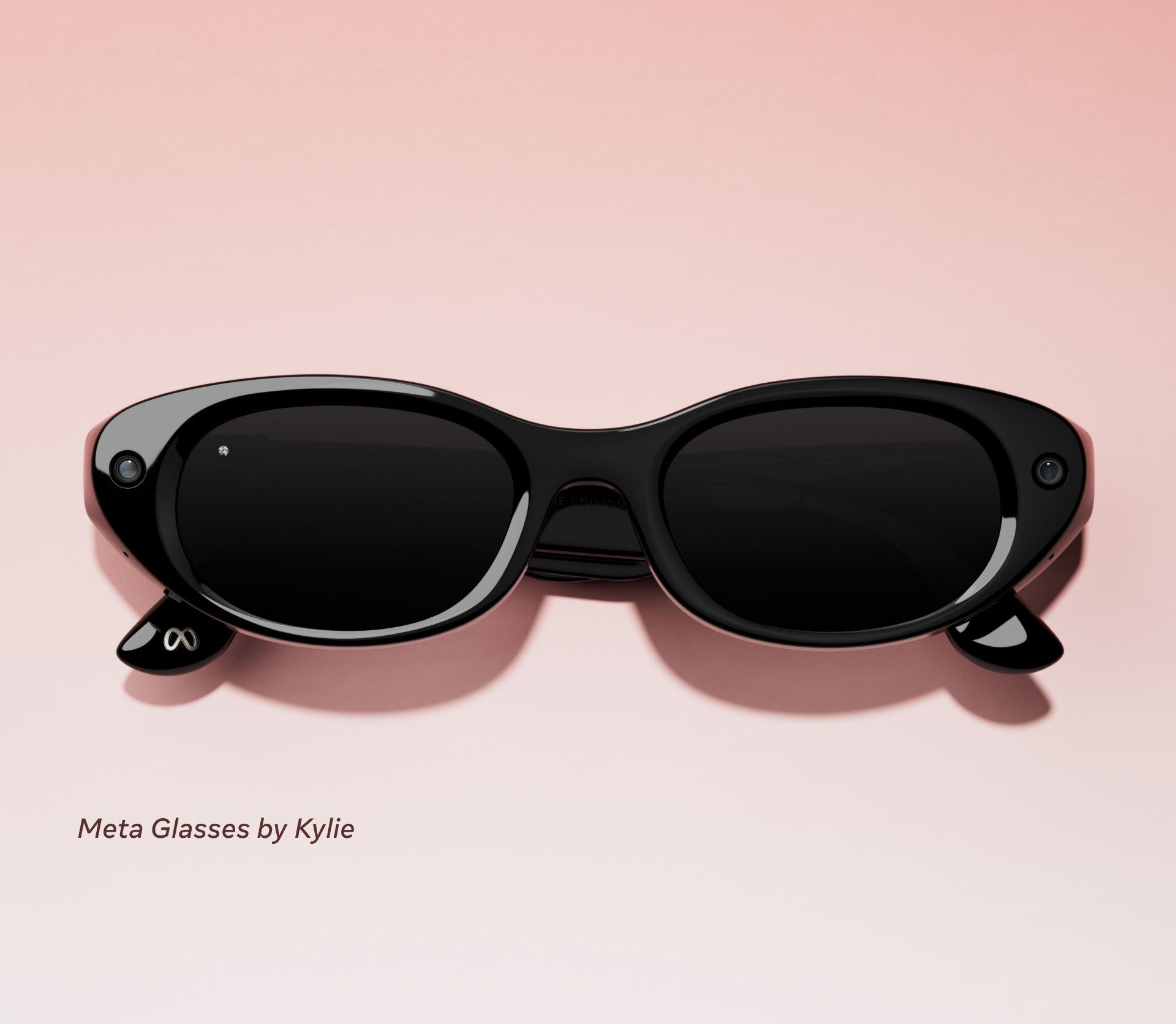 Schwarze Meta-Sonnenbrille auf rosa Hintergrund mit kleinen Kameras an den Rändern.