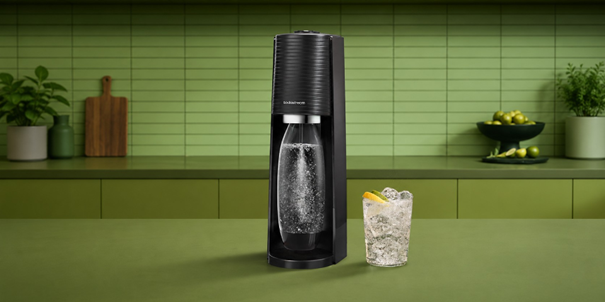 SodaStream-Sprudler mit einem Glas eisgekühltem Wasser in einer grässlich grünen Küche.