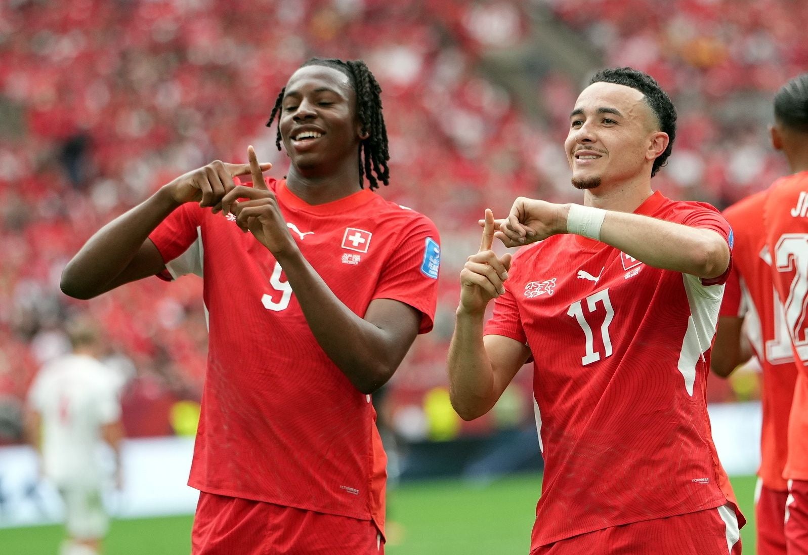 Zwei Schweizer Fußballspieler jubeln im roten Trikot bei einem WM-Spiel im Stadion.