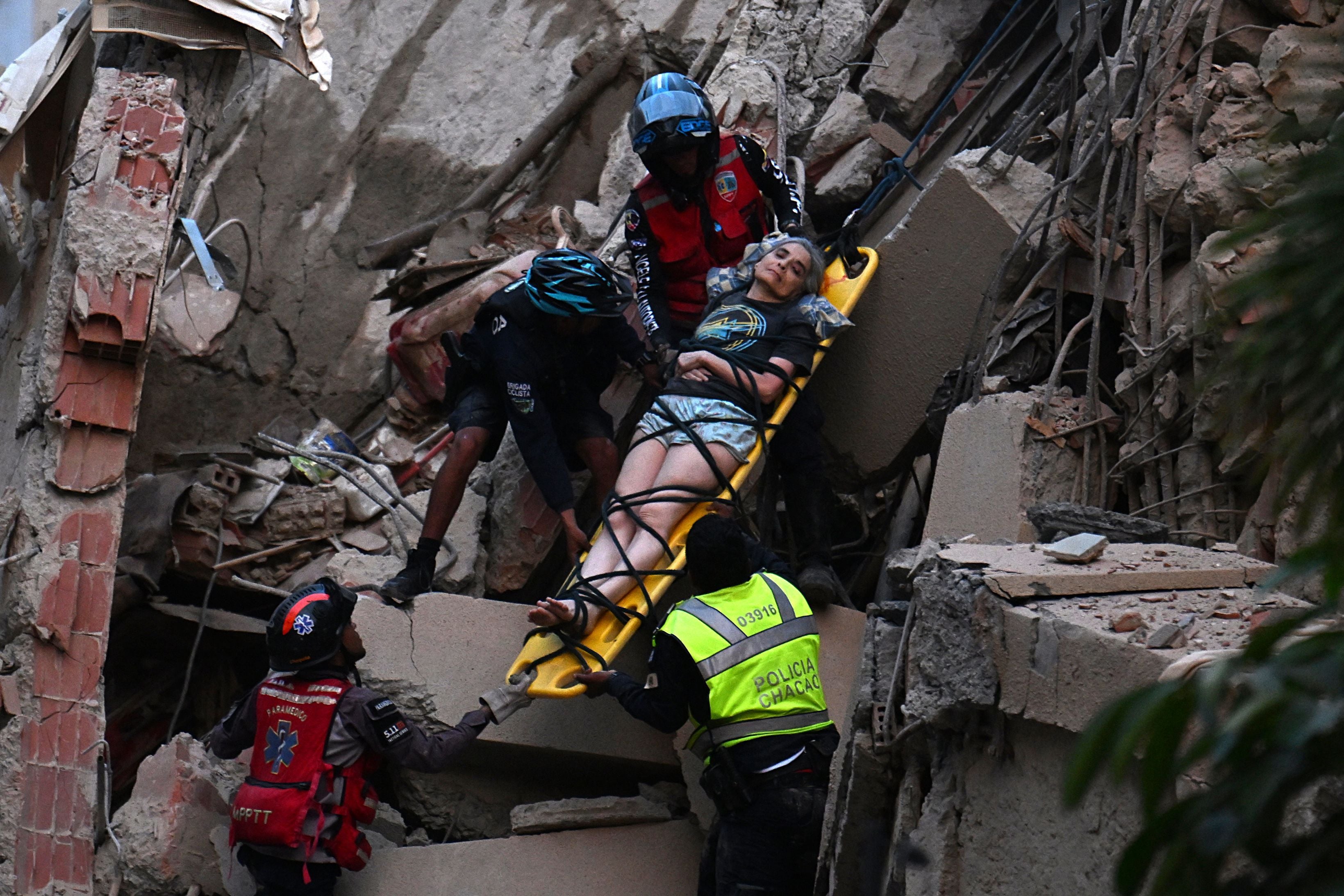 Rettungskräfte bergen eine Person auf einer Trage aus Trümmern eines eingestürzten Gebäudes.