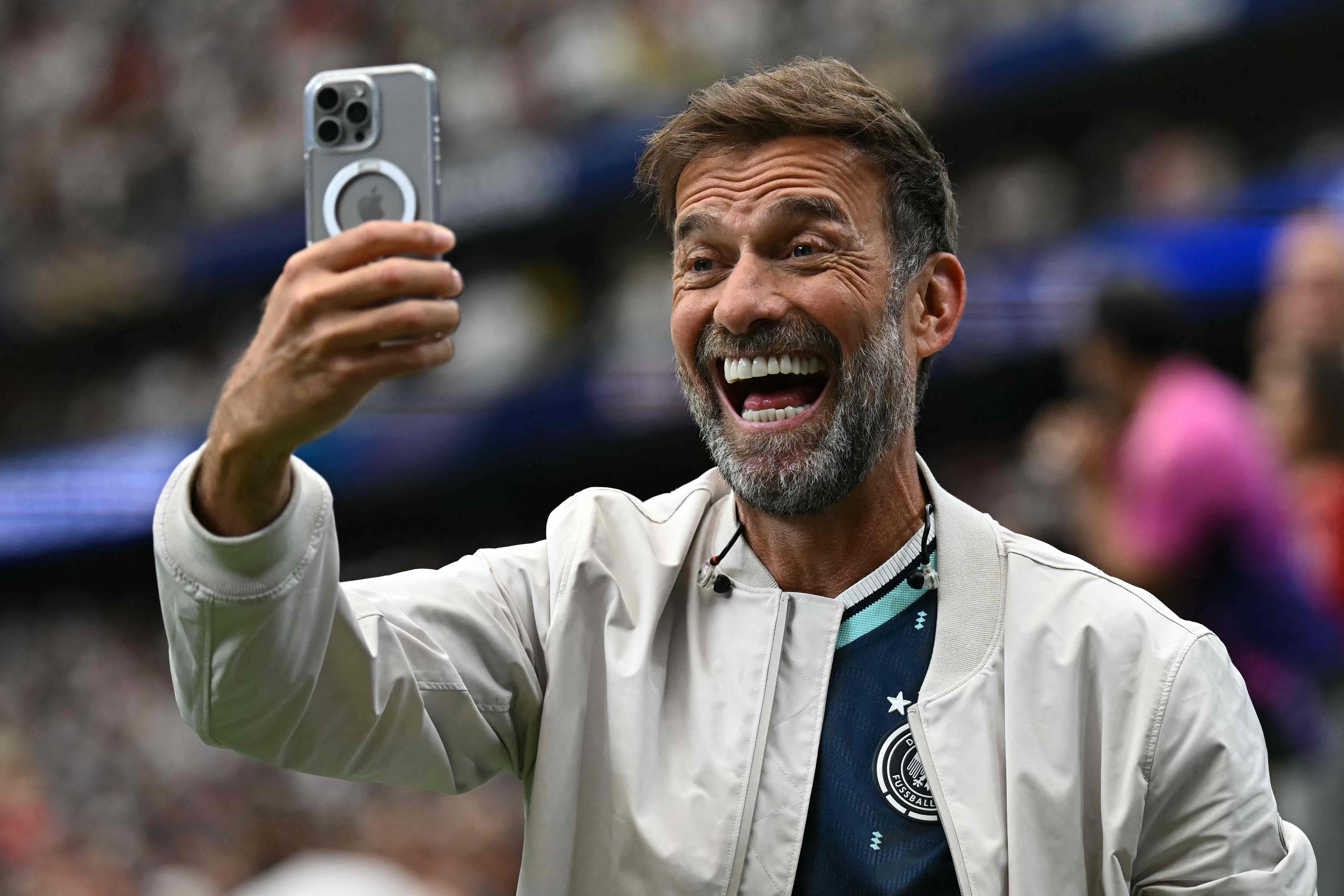 Ein Mann im Deutschlandtrikot macht ein Selfie im Stadion während eines Fußballspiels.
