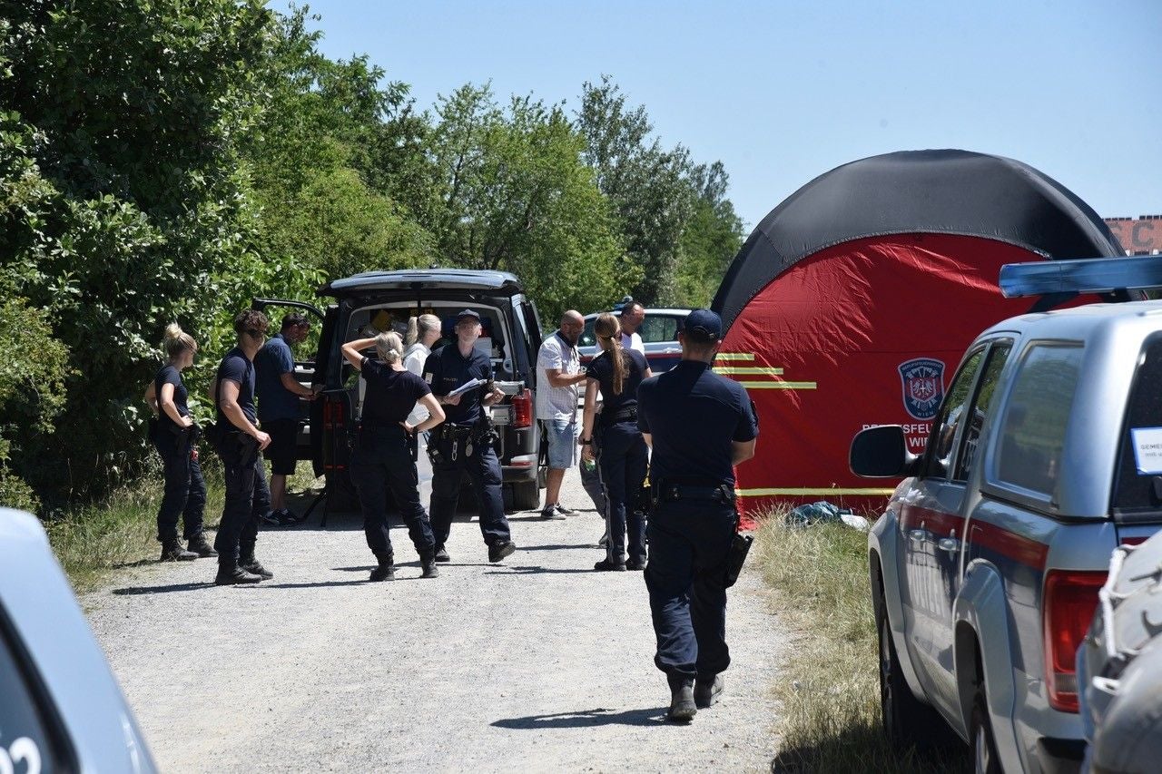 Polizei und Einsatzkräfte an einem Einsatzort mit roten Zelt und mehreren Fahrzeugen im Freien.