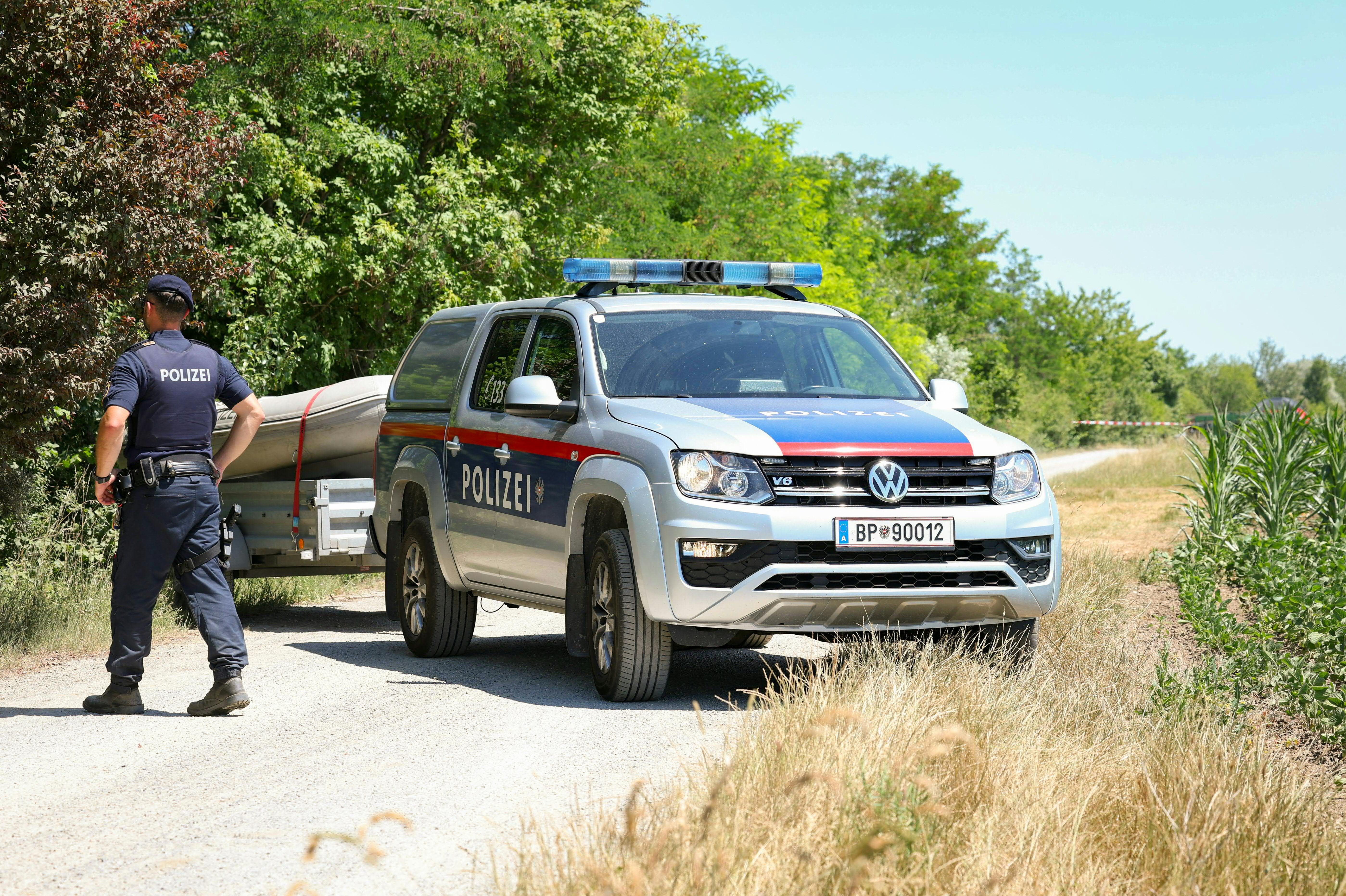 Polizeifahrzeug mit Boot und Polizist stehen auf einem Weg am Marchfeldkanal bei Gerasdorf.
