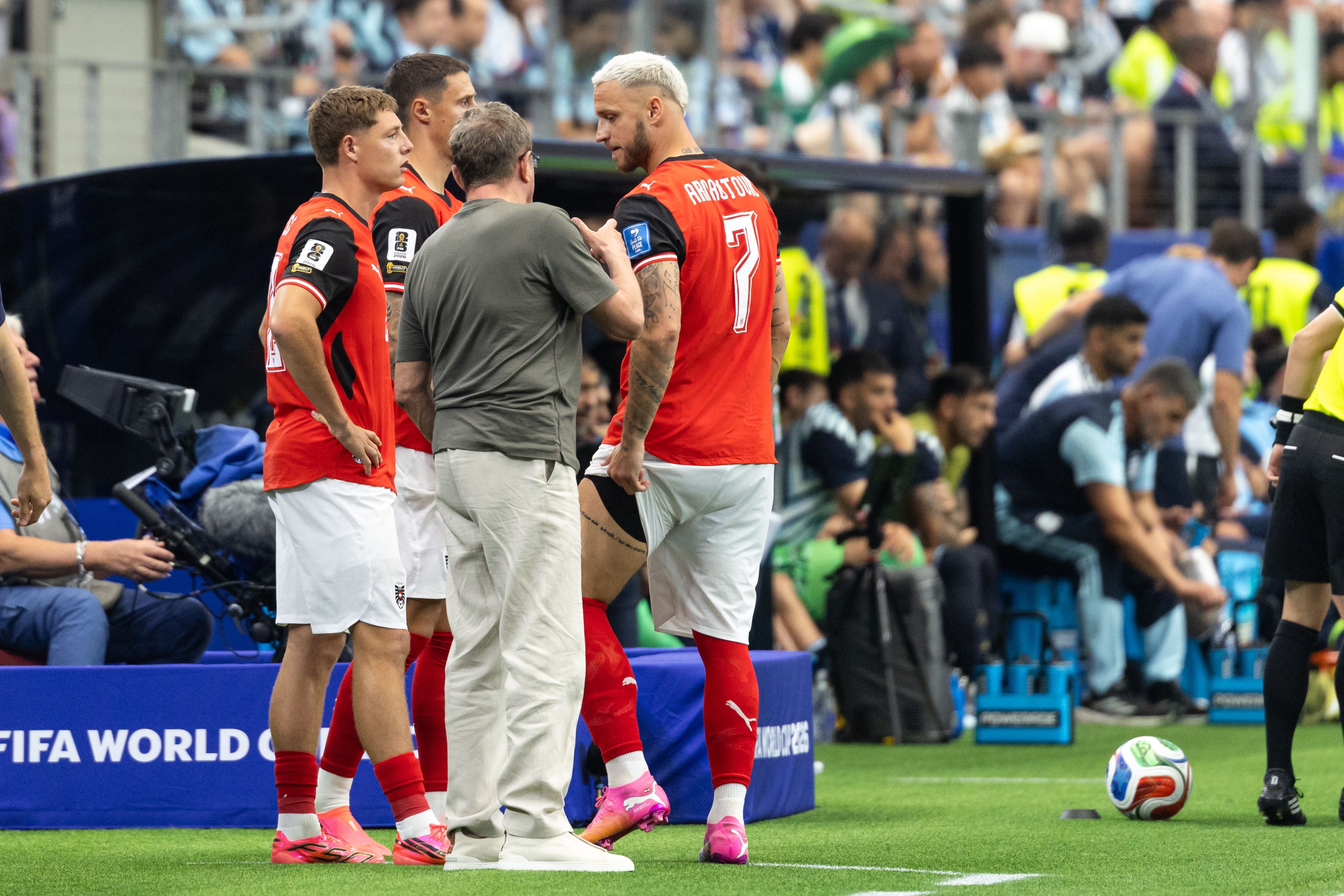 Trainer und österreichische Spieler beraten sich am Spielfeldrand während eines WM-Spiels.