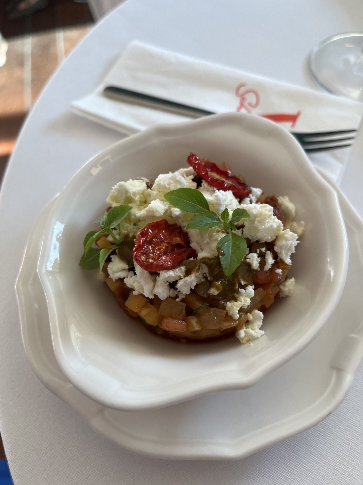 Ein Vorspeisenteller mit Gemüse, Feta, getrockneten Tomaten und frischen Kräutern.