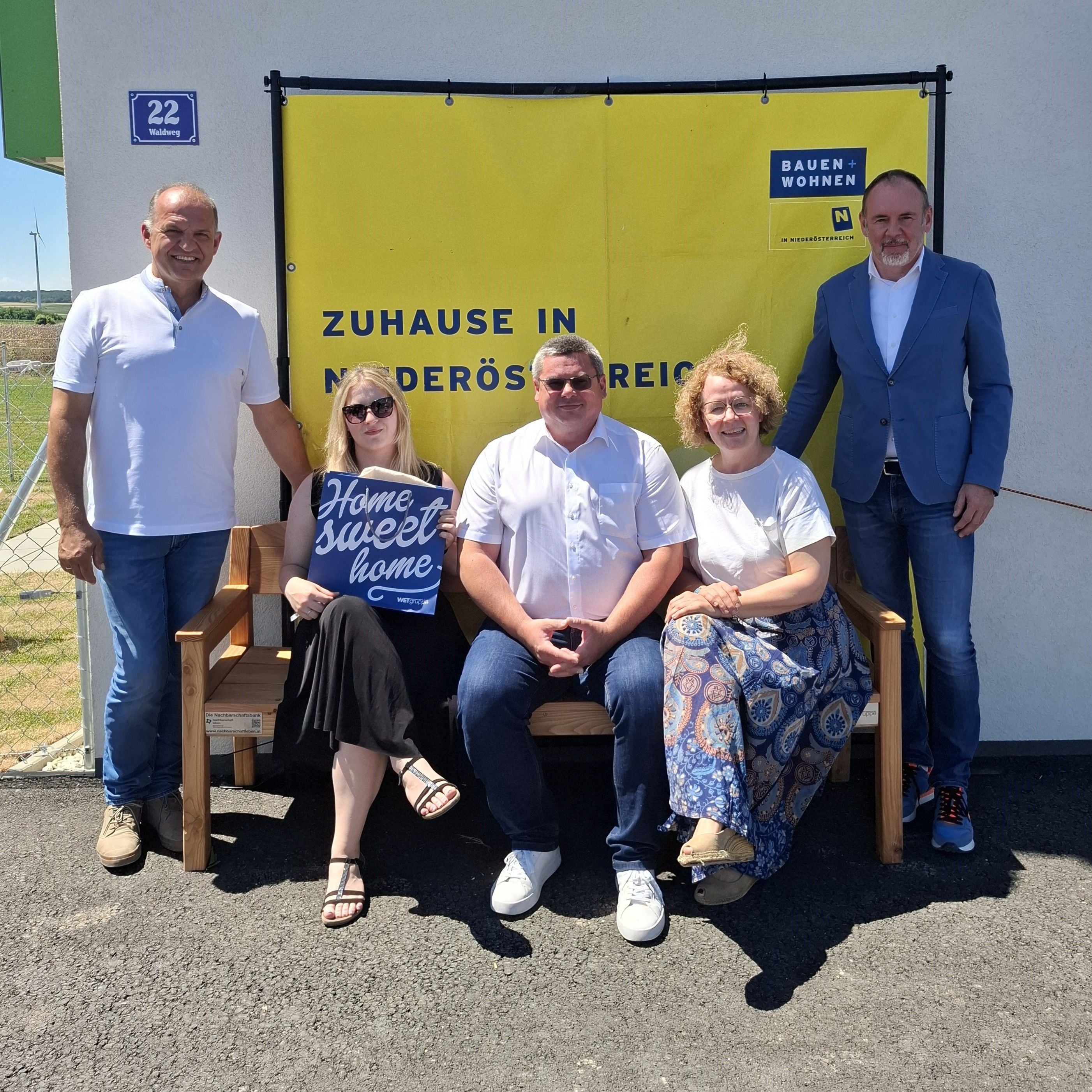 Fünf Personen posieren vor einem gelben Banner mit der Aufschrift „Zuhause in Niederösterreich“.