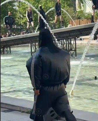 Person in einer aufgeblasenen schwarzen Rick Owens x Adidas Jacke bei einer Modenschau im Freien.