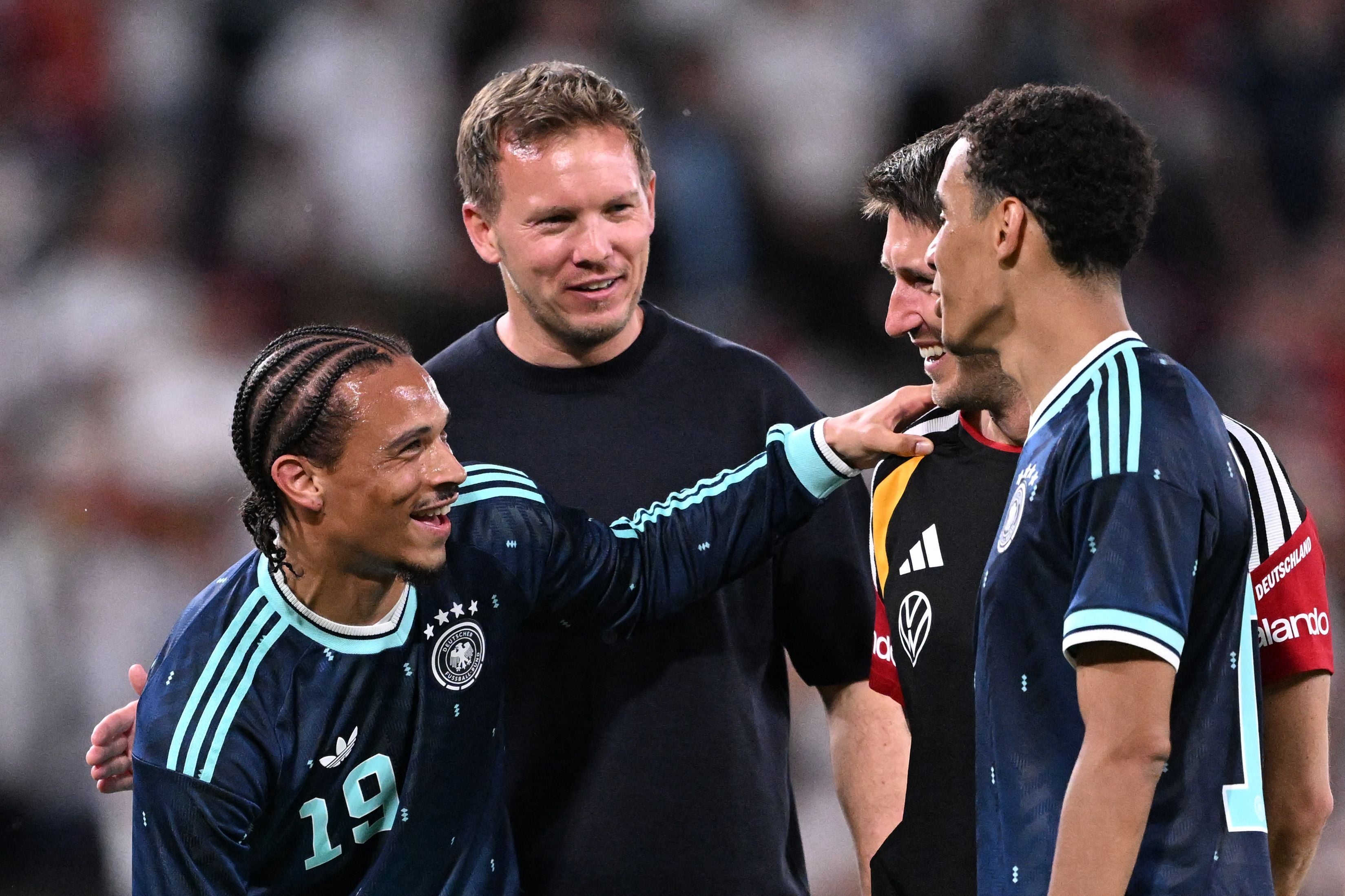 Vier Personen im deutschen Fußballtrikot feiern auf dem Spielfeld nach einem Spiel.
