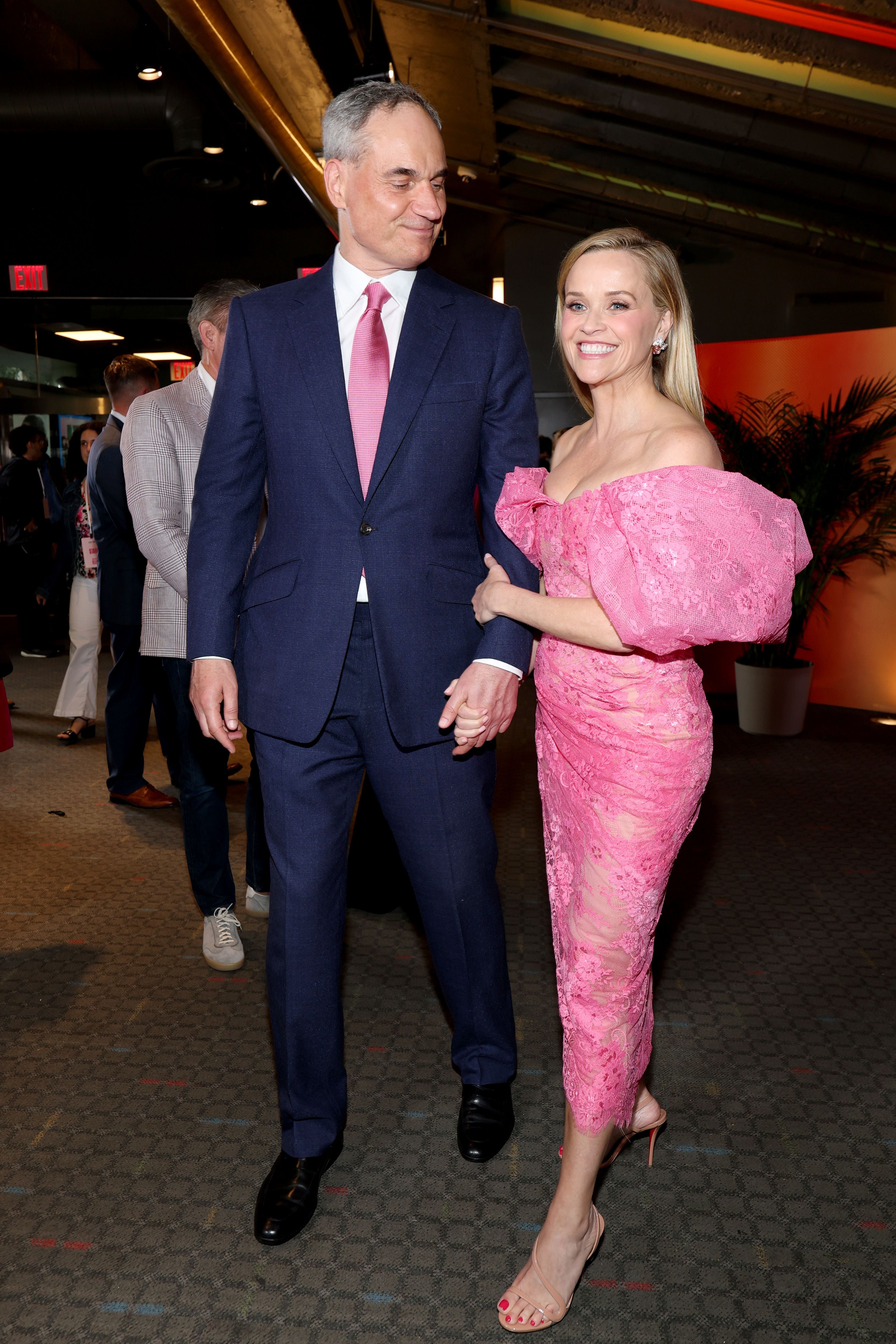 Ein Mann im Anzug und eine Frau im pinken Kleid posieren gemeinsam auf einem Event.