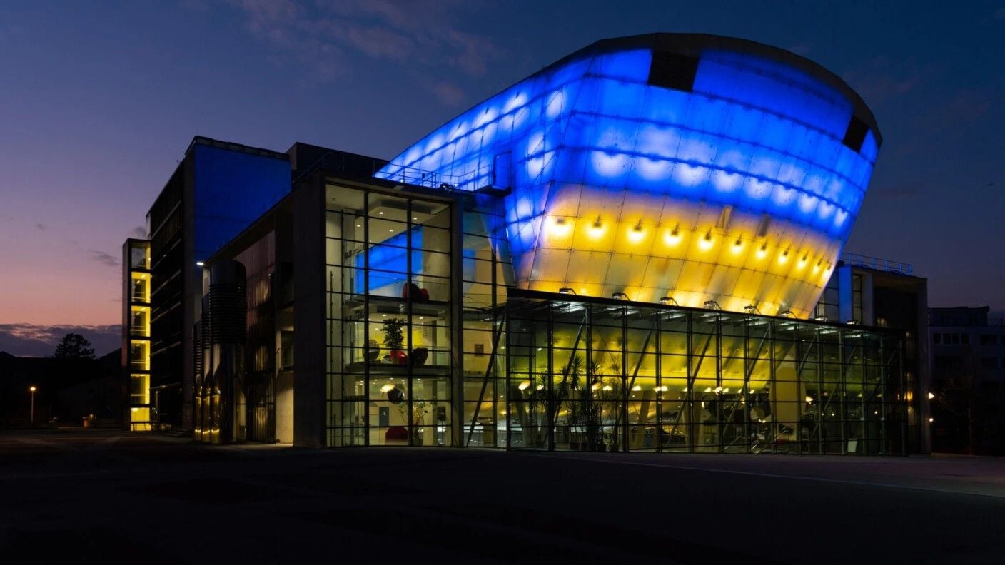 Das Festspielhaus St. Pölten bei Nacht, beleuchtet in Blau und Gelb.