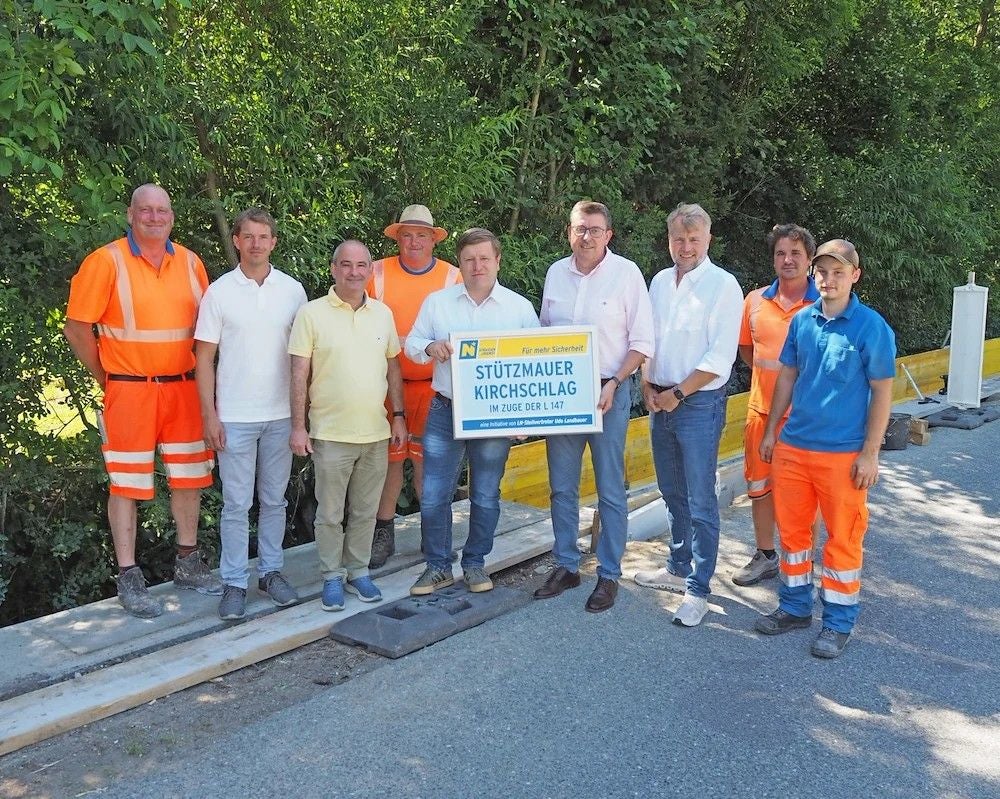 Mehrere Menschen stehen auf einer Baustelle und halten ein Schild zu einem Bauprojekt.