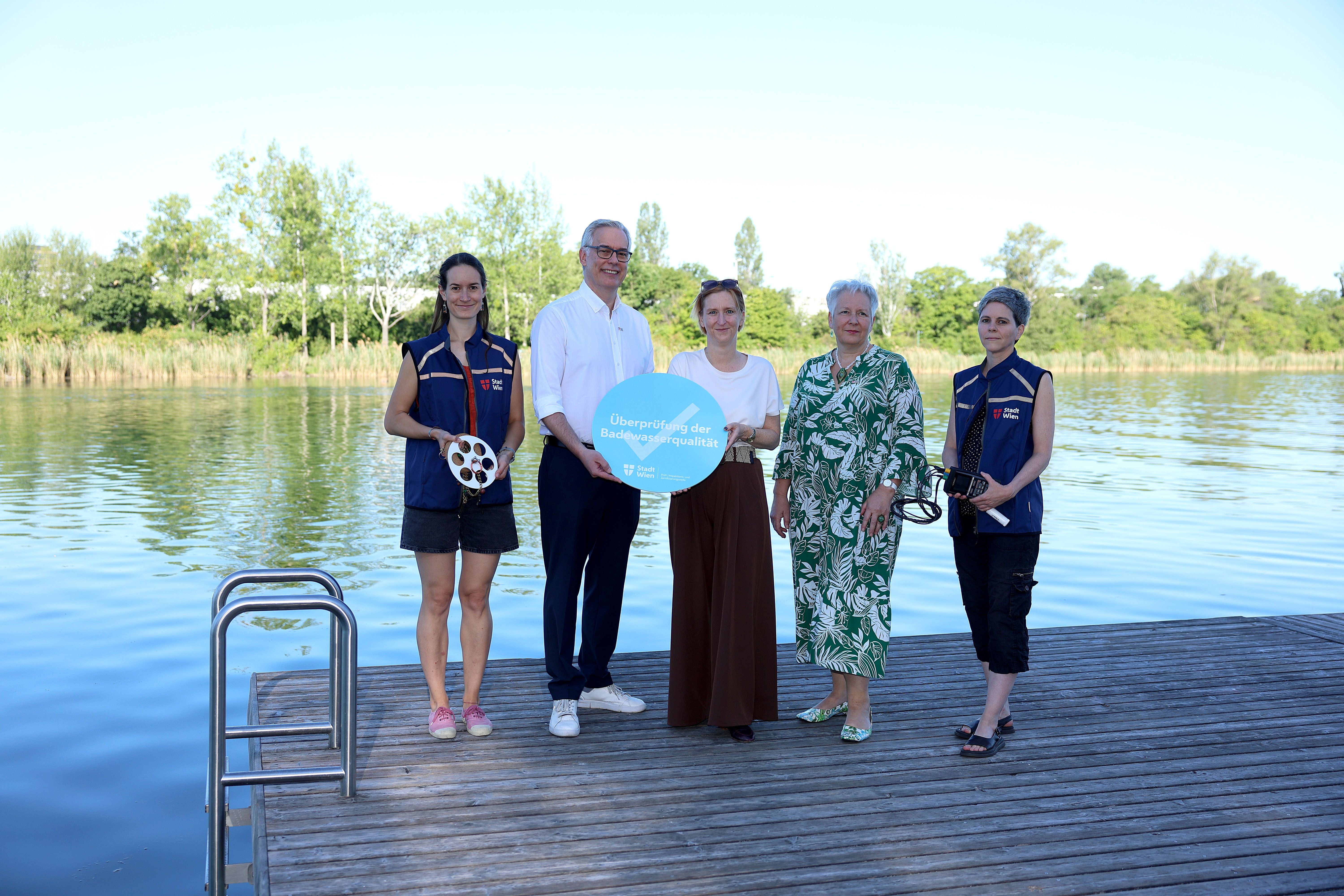 Fünf Personen stehen auf einem Steg an der Alten Donau zur Überprüfung der Badewasserqualität.