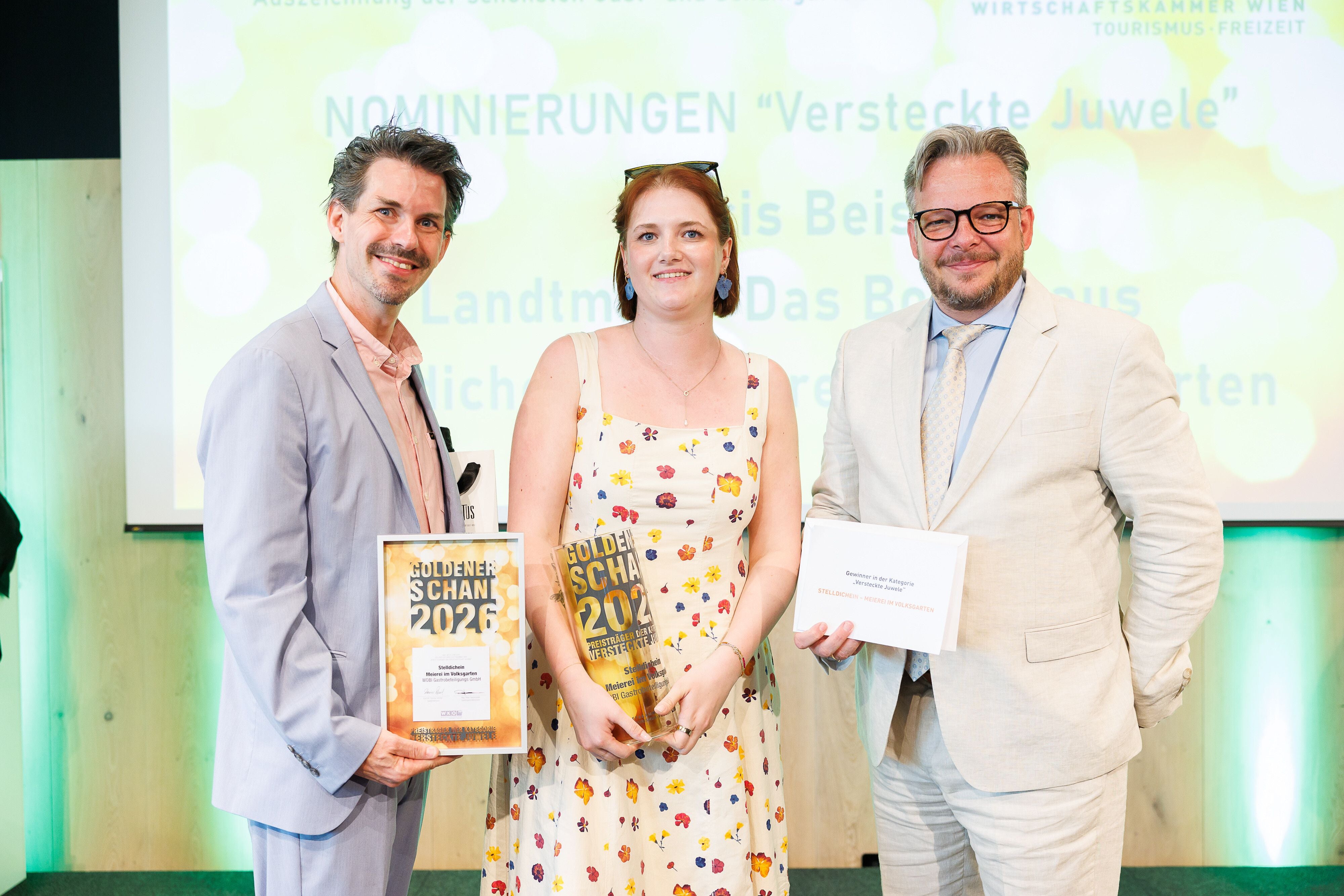 Drei Personen in festlicher Kleidung halten Auszeichnungen bei einer WKW-Preisverleihung.