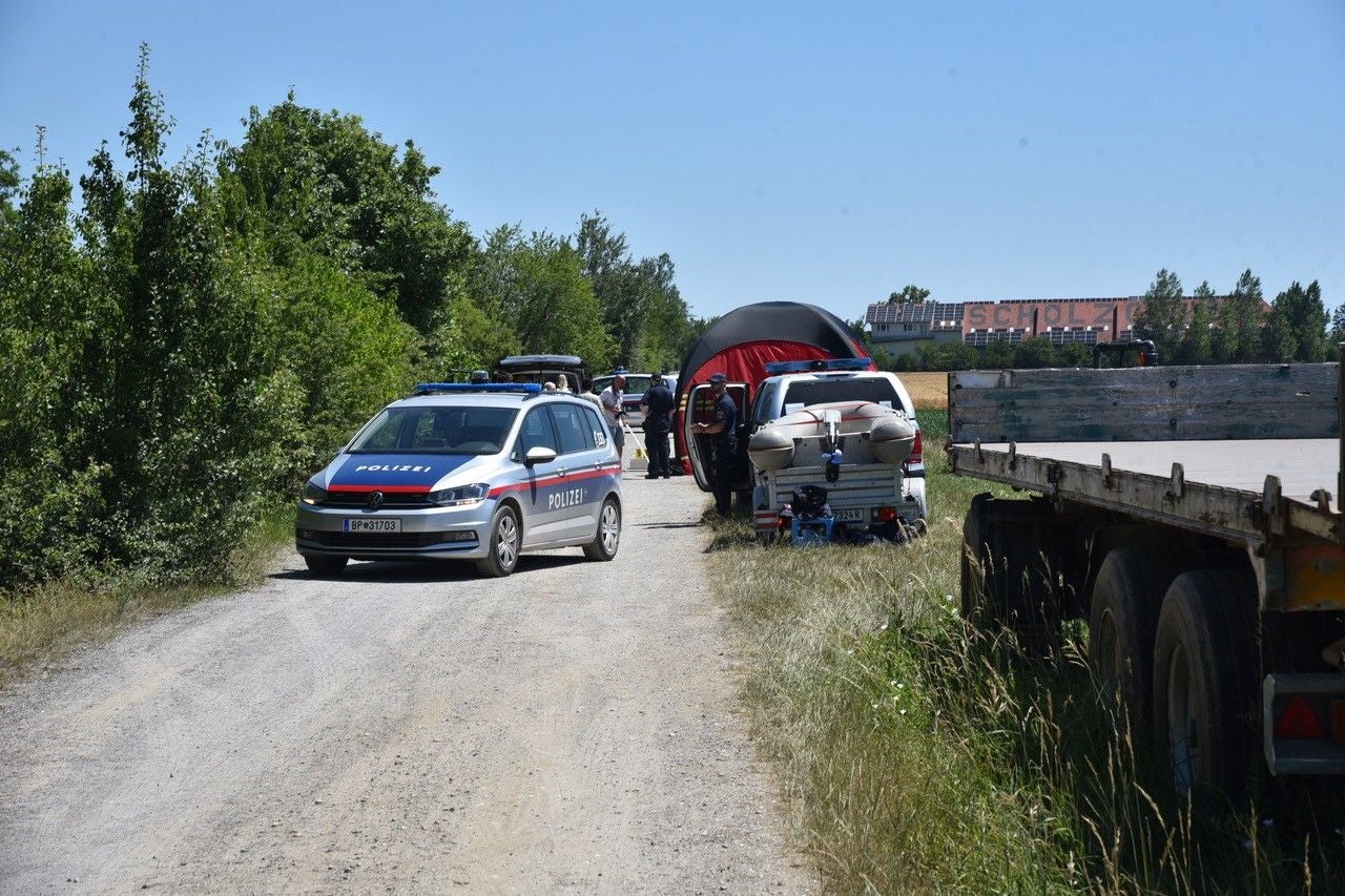 Polizeifahrzeuge und Einsatzkräfte an einem Feldweg nahe einem Kanal, Einsatznachbesprechung.