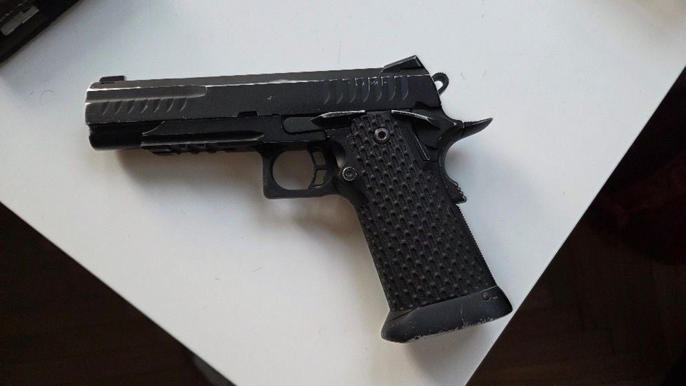 Eine schwarze Softairpistole liegt auf einer weißen Oberfläche.