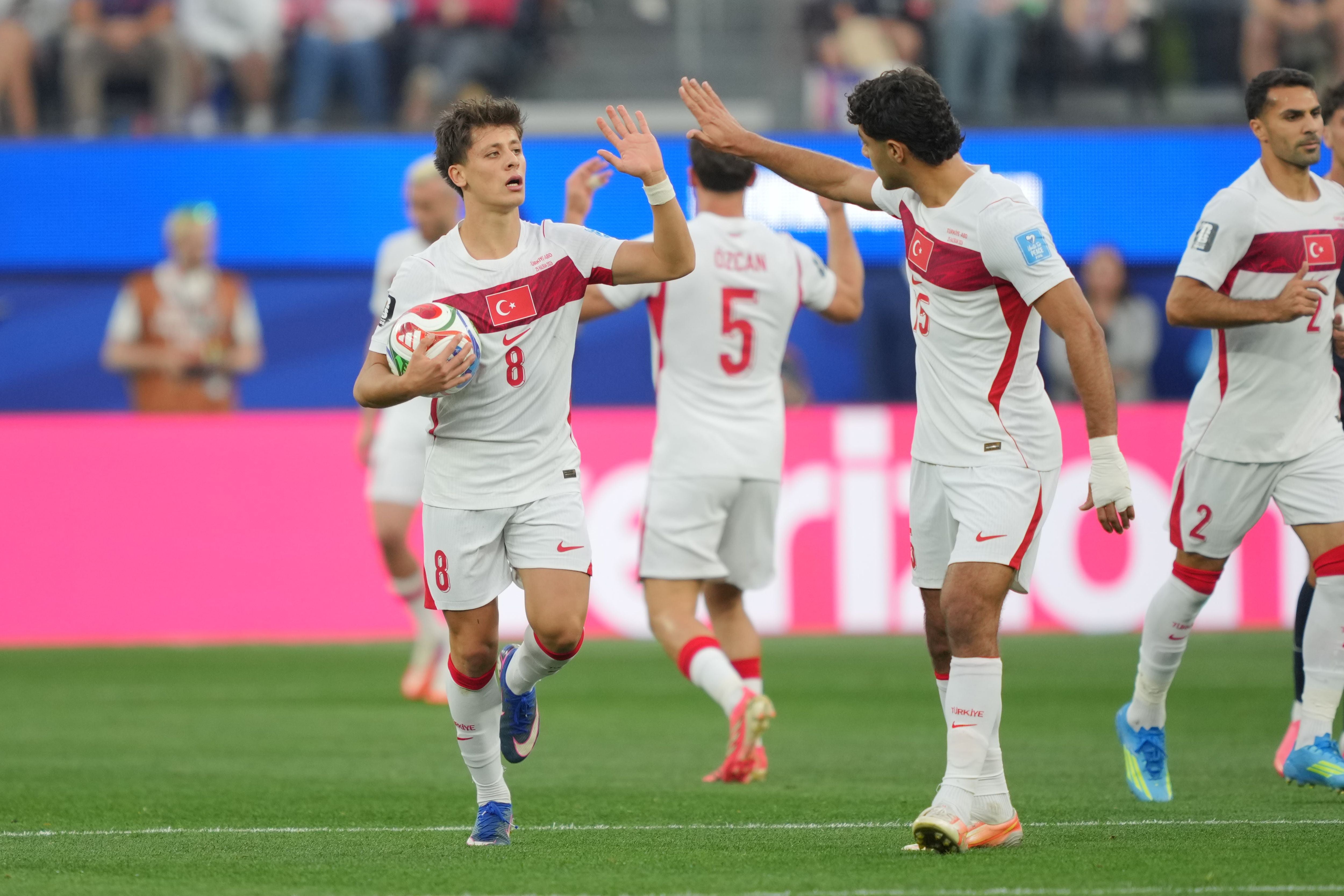 Türkische Fußballspieler jubeln nach einem Tor in weißen Trikots beim Spiel gegen die USA.