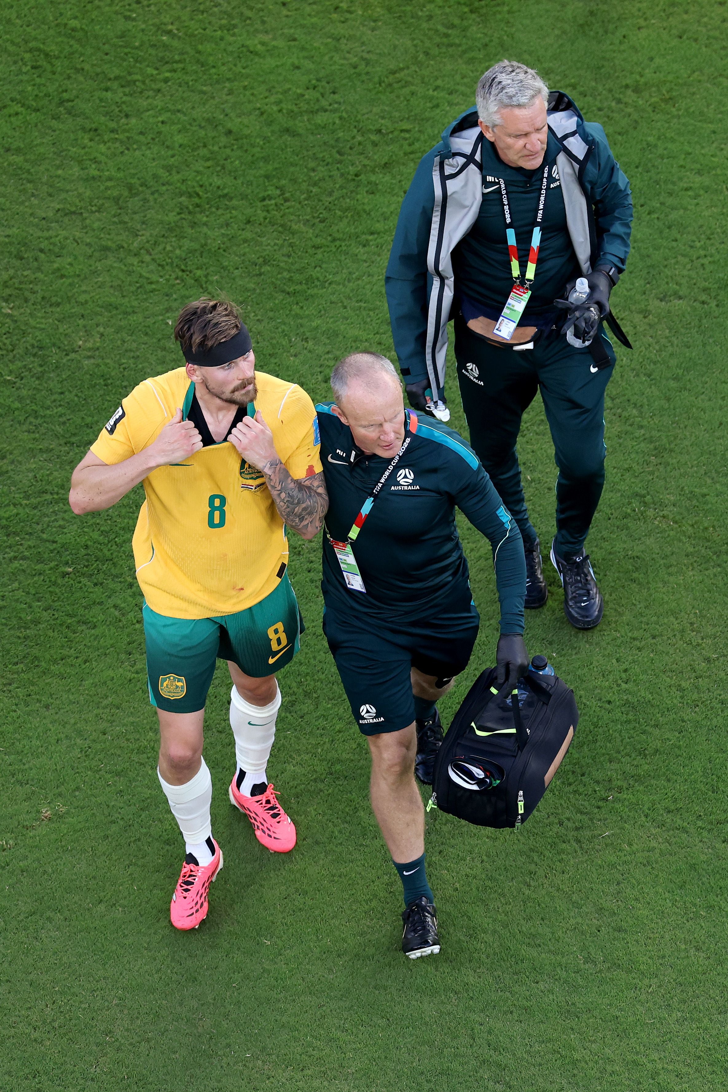 Ein australischer Fußballspieler wird nach einer Verletzung von zwei Sanitätern begleitet.