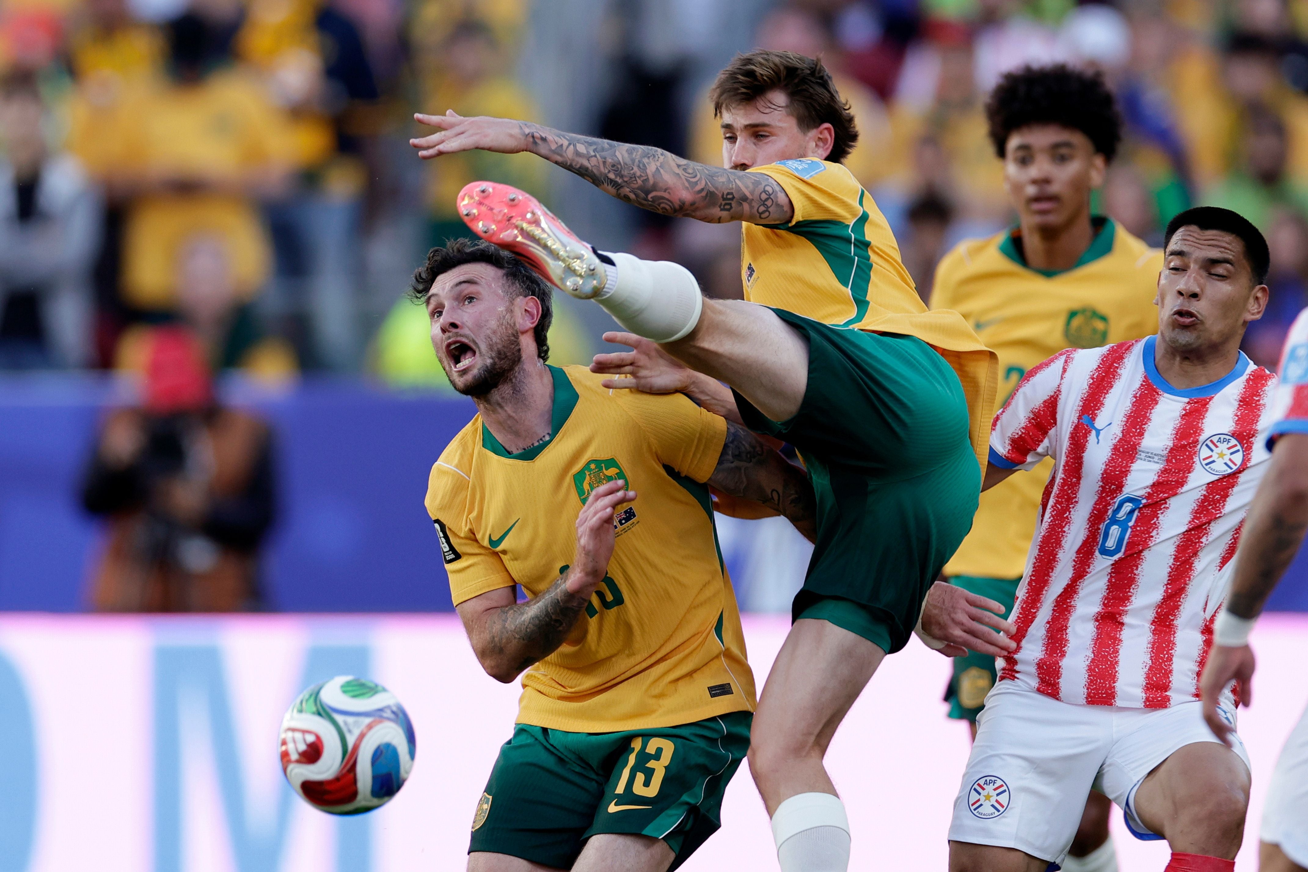 Australische und paraguayische Fußballer kämpfen dynamisch um den Ball im Stadion.