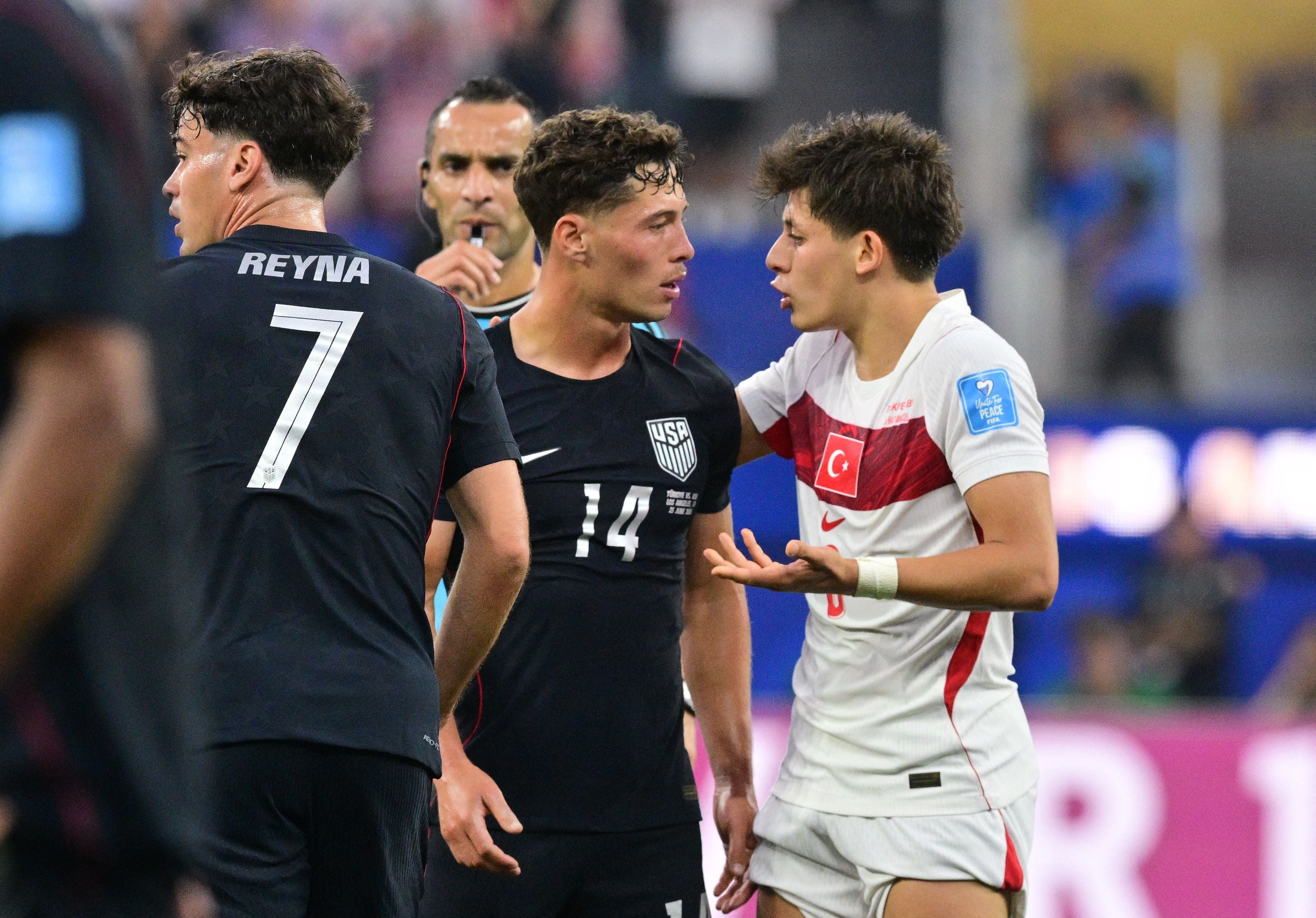 Spieler der USA und Türkei diskutieren während eines Fußballspiels auf dem Spielfeld.