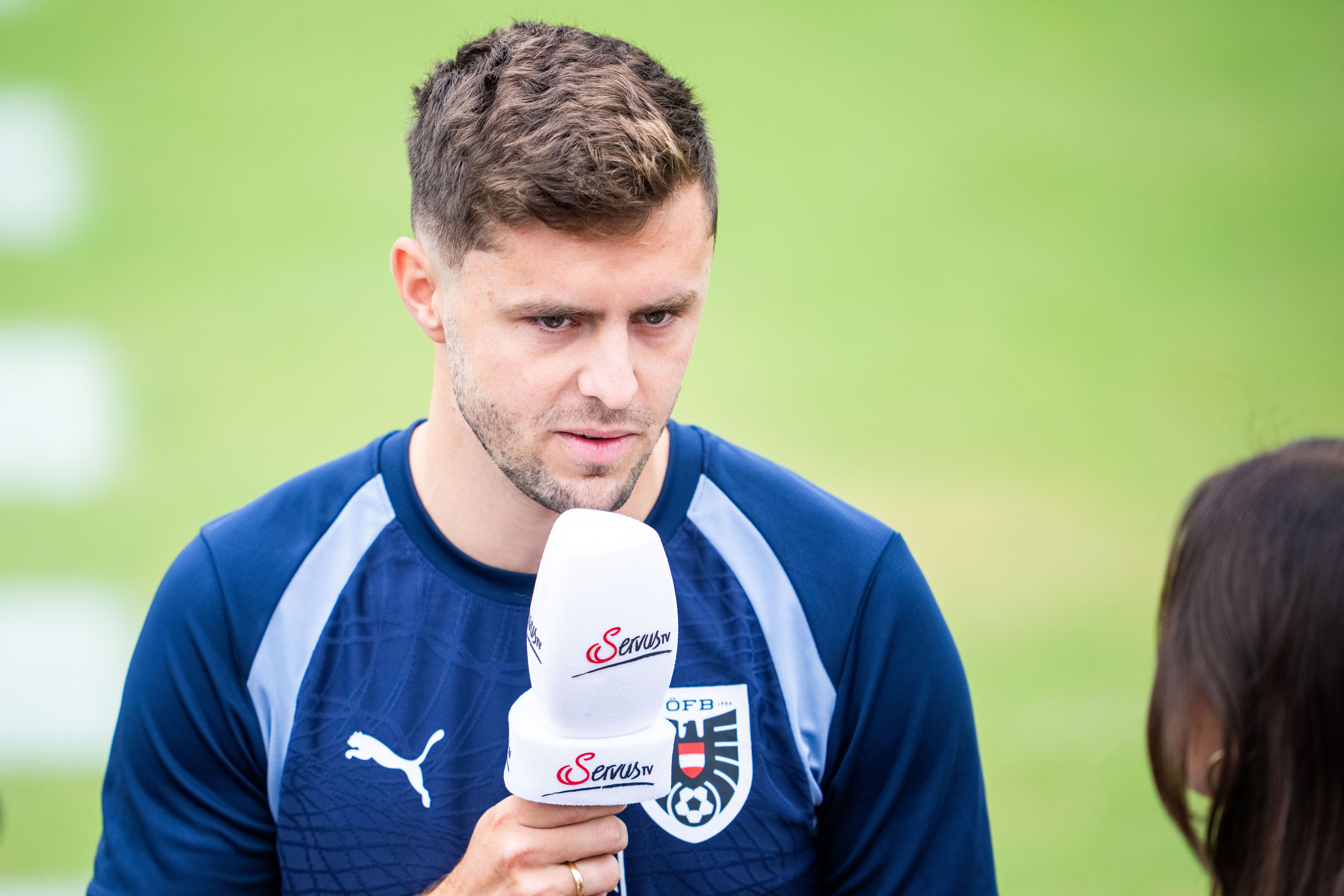 Ein Fußballspieler im blauen Trainingsanzug gibt ein Interview mit ServusTV-Mikrofon.