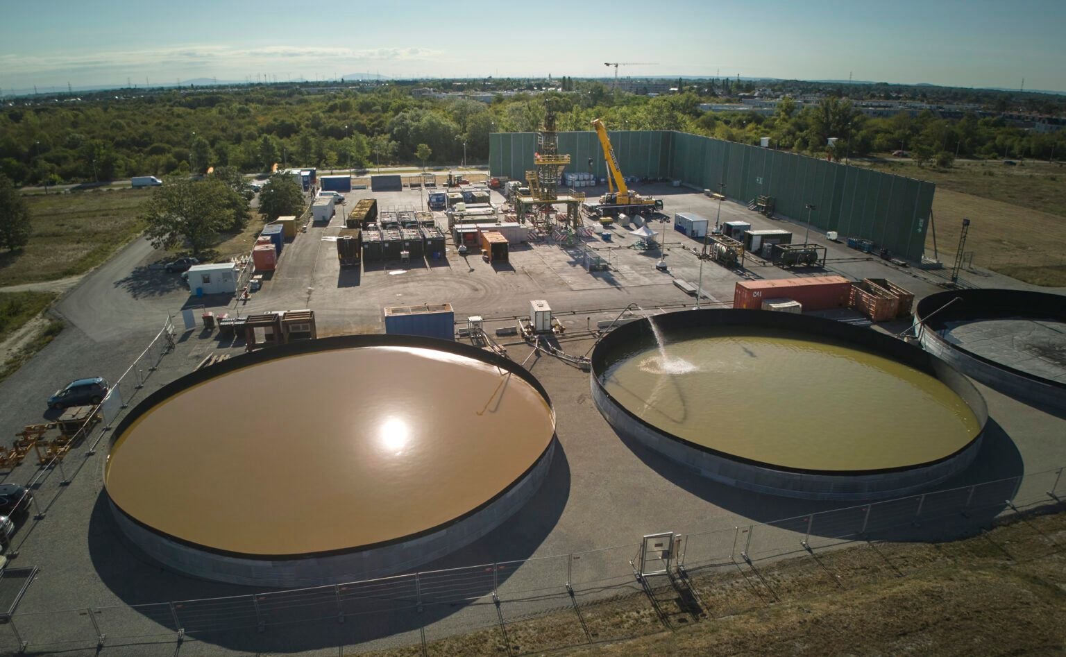 Luftbild der Tiefengeothermie-Anlage in Wien Aspern mit großen Wasserbecken und Industrieanlagen.