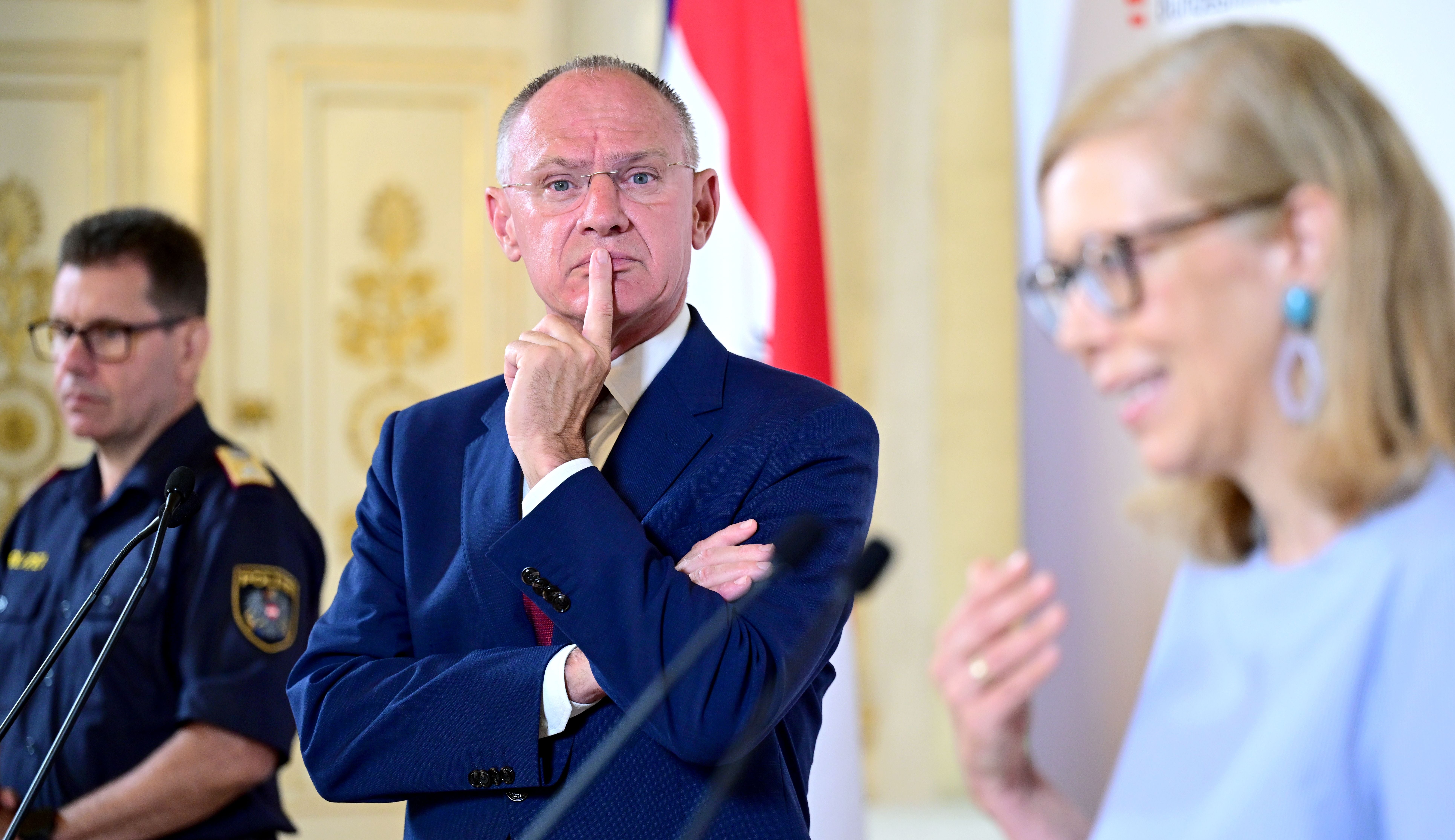 Drei Personen sprechen bei einer Pressekonferenz in einem prunkvollen Saal in Wien.