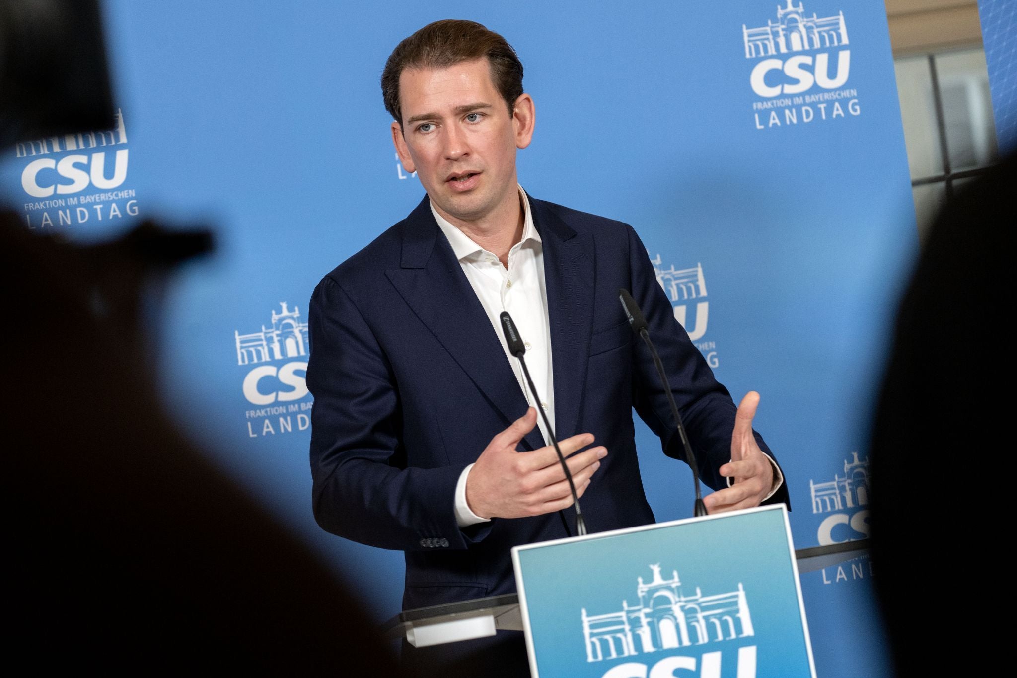 Ein Mann im Anzug spricht bei einer Pressekonferenz vor einem CSU-Landtagsfraktion-Hintergrund.