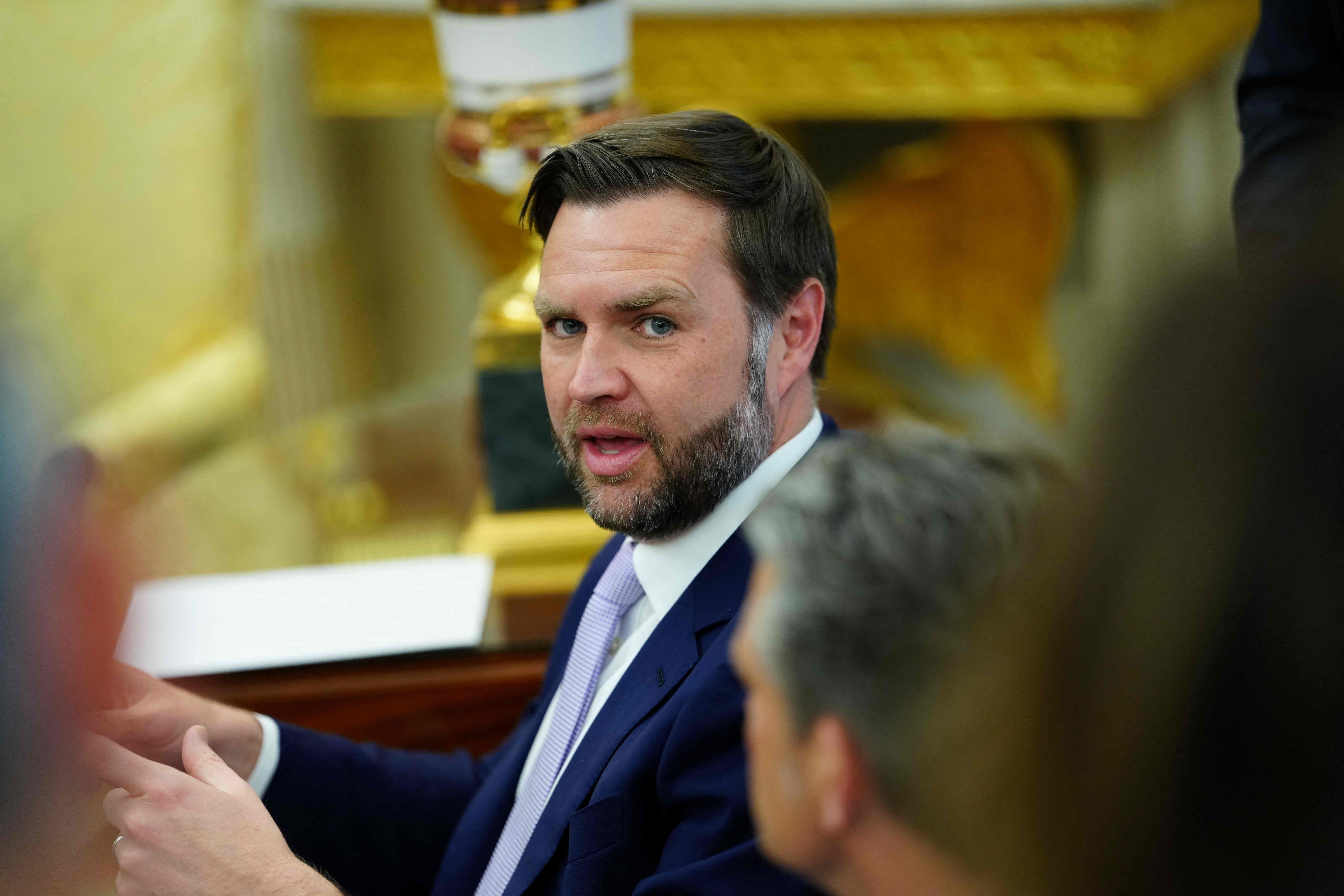 Ein Mann im Anzug spricht während eines Treffens im Oval Office mit mehreren Personen.