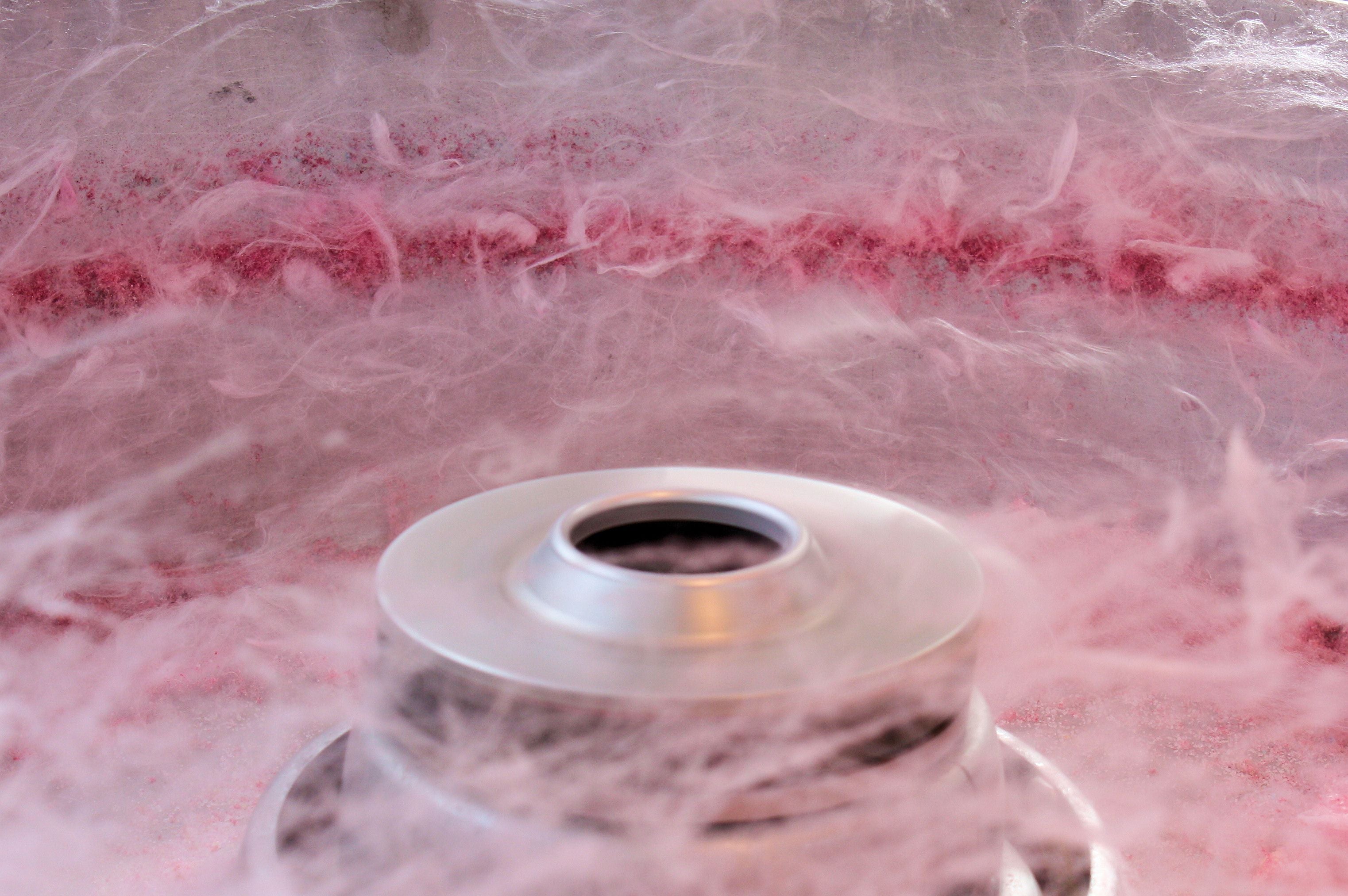 Zuckerwattemaschine wirbelt rosa Zuckerwatte in der Luft.