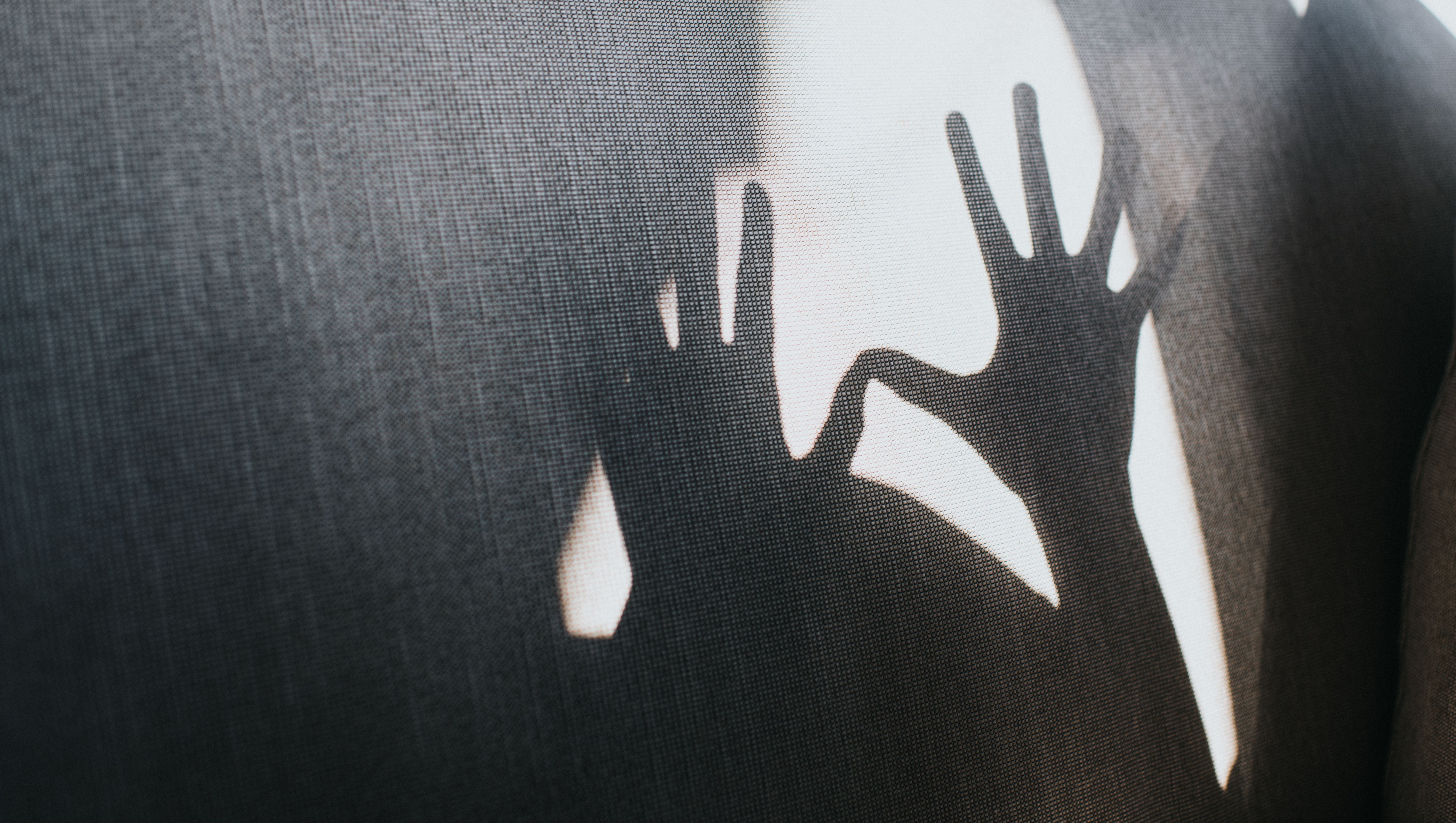 Schatten von zwei ausgestreckten Händen auf einer Oberfläche mit viel Freiraum.