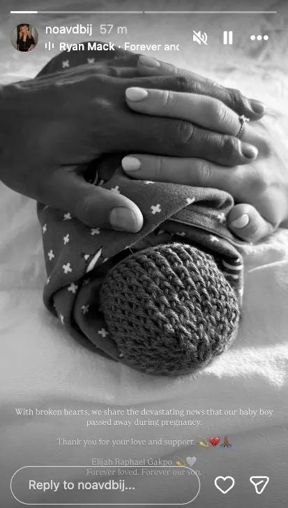 Zwei Hände halten ein in eine Decke gewickeltes Baby mit Strickmütze.