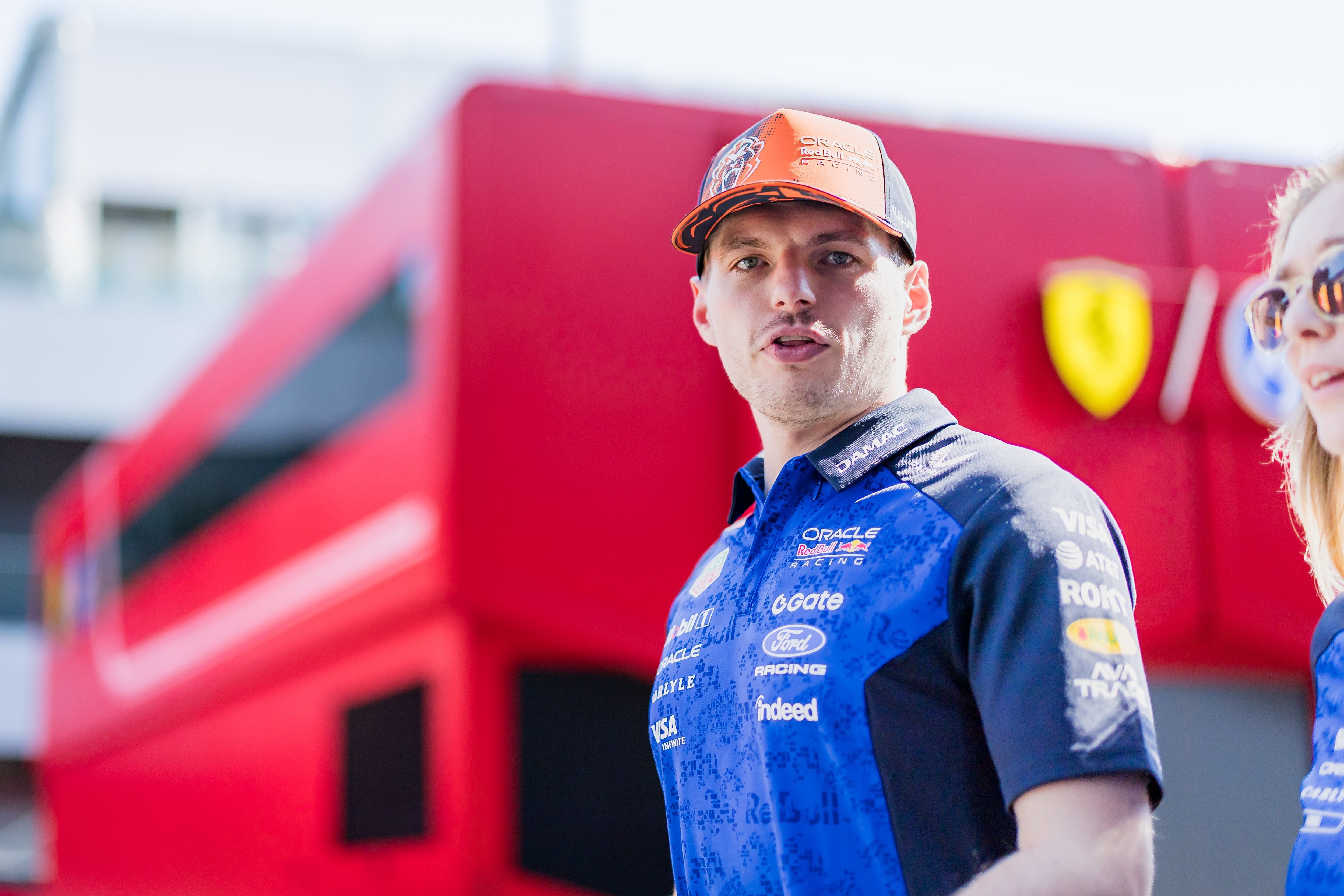 Ein Mann im Red Bull Racing Outfit steht vor einem roten Ferrari-Truck am Rennwochenende.