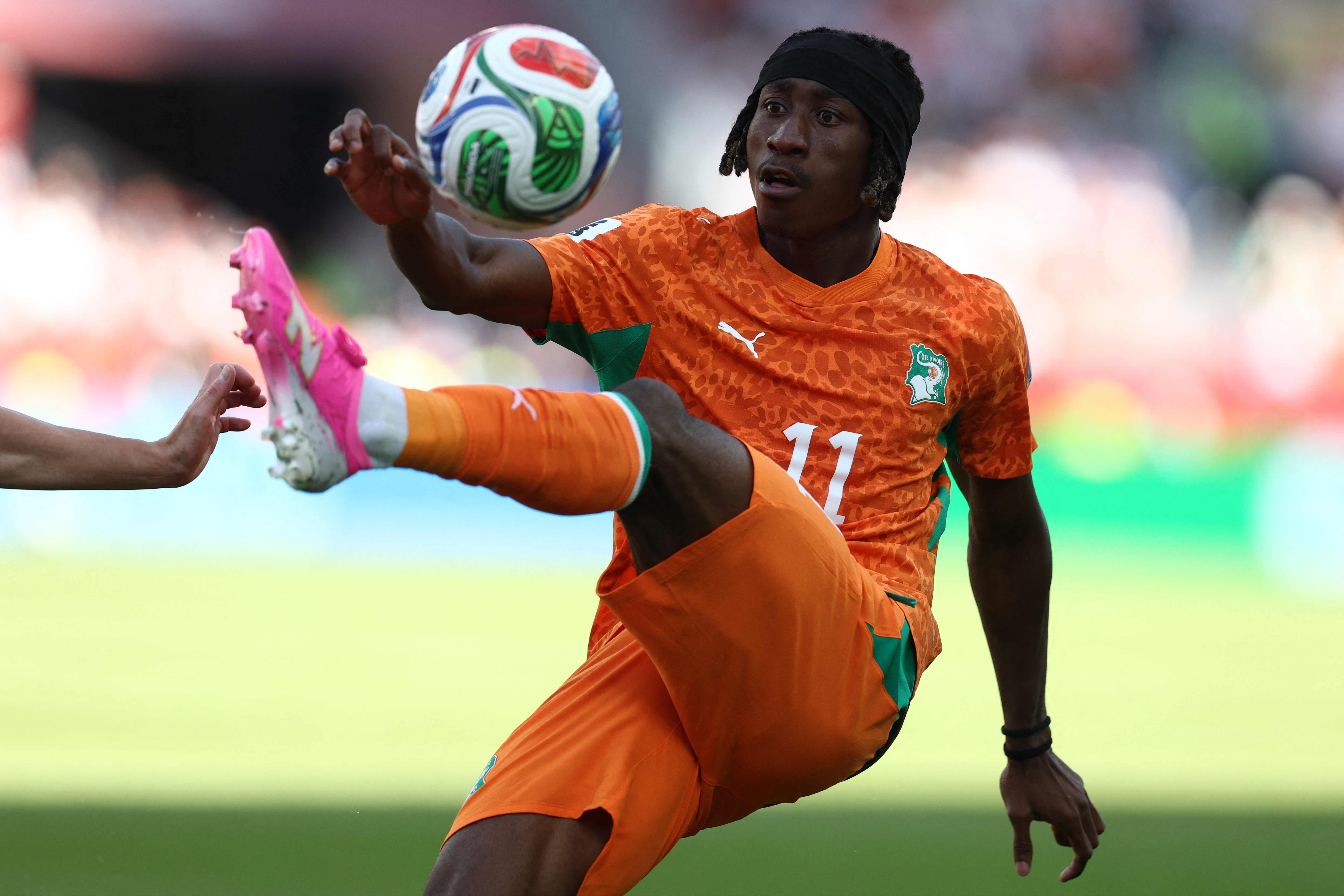 Ein ivorischer Fußballspieler kontrolliert im Sprung den Ball während eines Spiels.