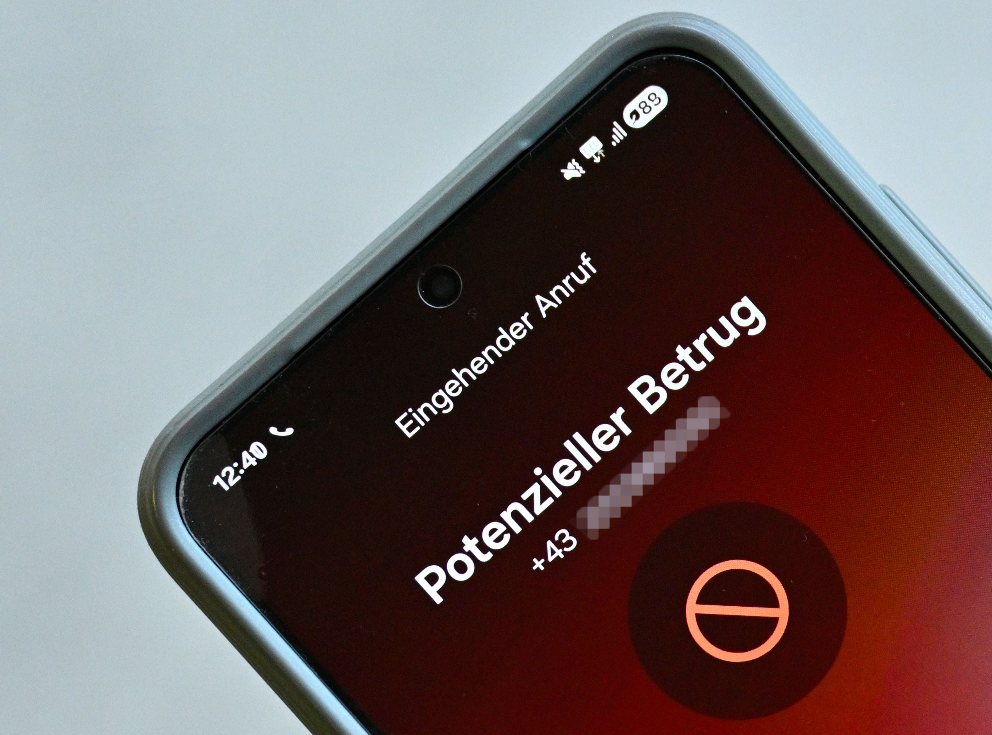 Smartphone-Bildschirm zeigt Warnung vor einem potenziellen Betrugsanruf mit österreichischer Nummer.