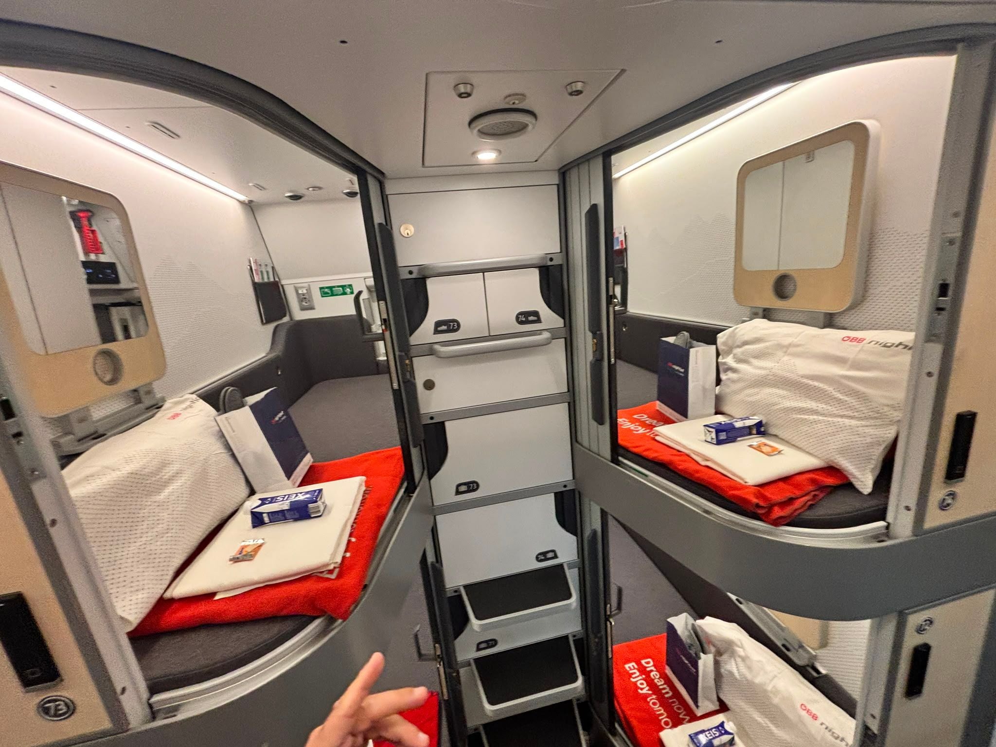 Moderne Mini-Schlafkabinen im Nightjet-Zug mit Bett, Kissen und Gepäckablage.