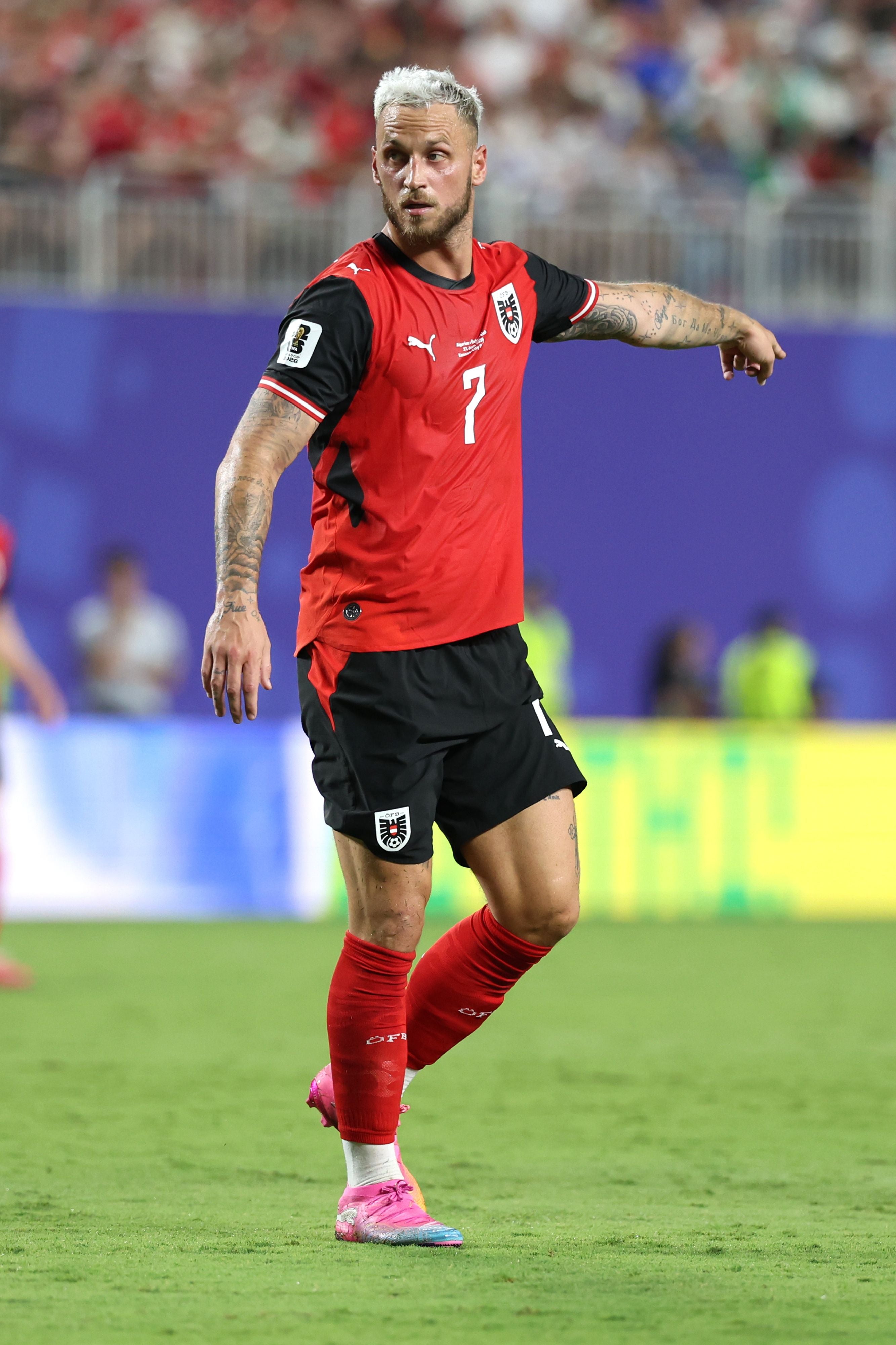 Ein österreichischer Fußballspieler im roten Trikot zeigt während eines Spiels in eine Richtung.
