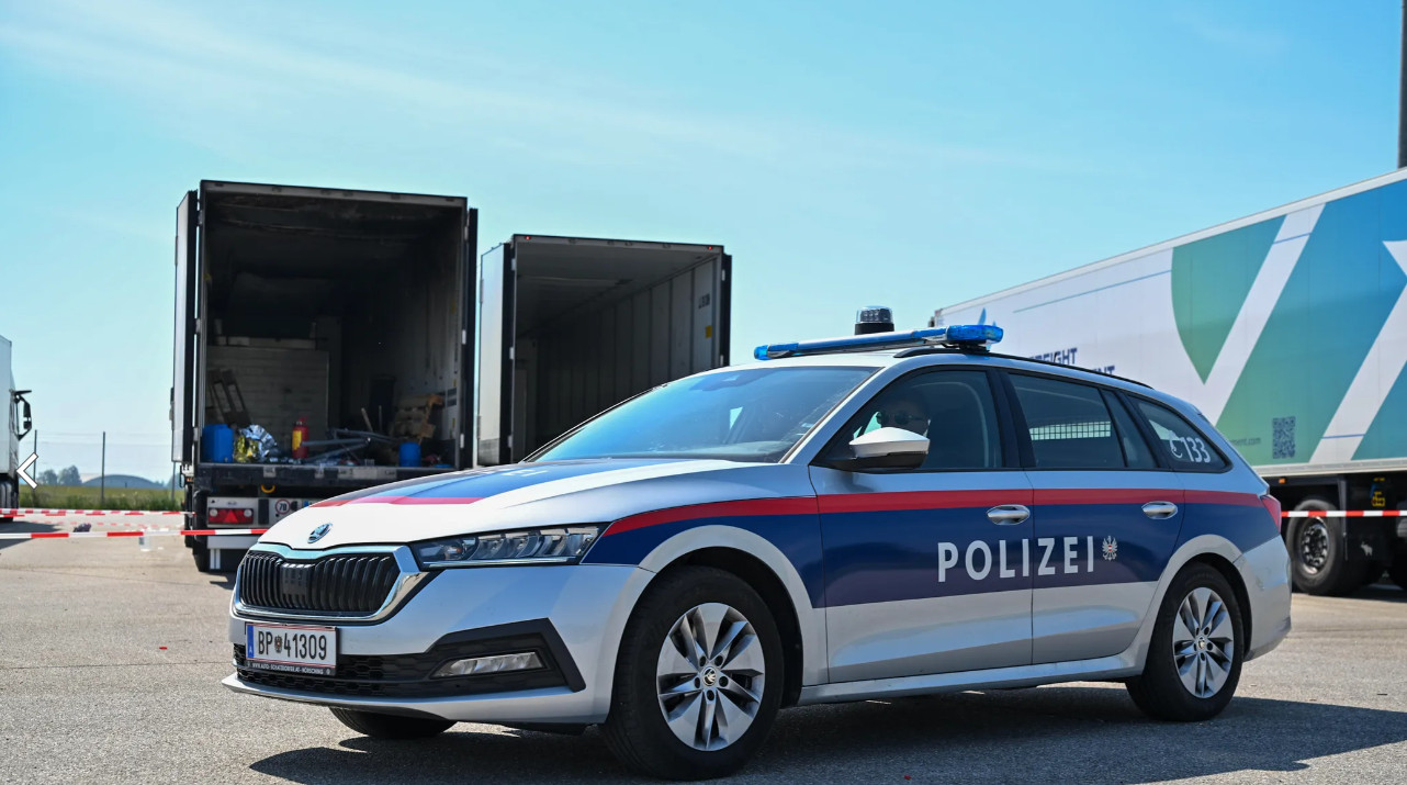 Ein Polizeiauto steht vor einem Sattelanhänger mit offener, ausgebrannter Ladefläche.