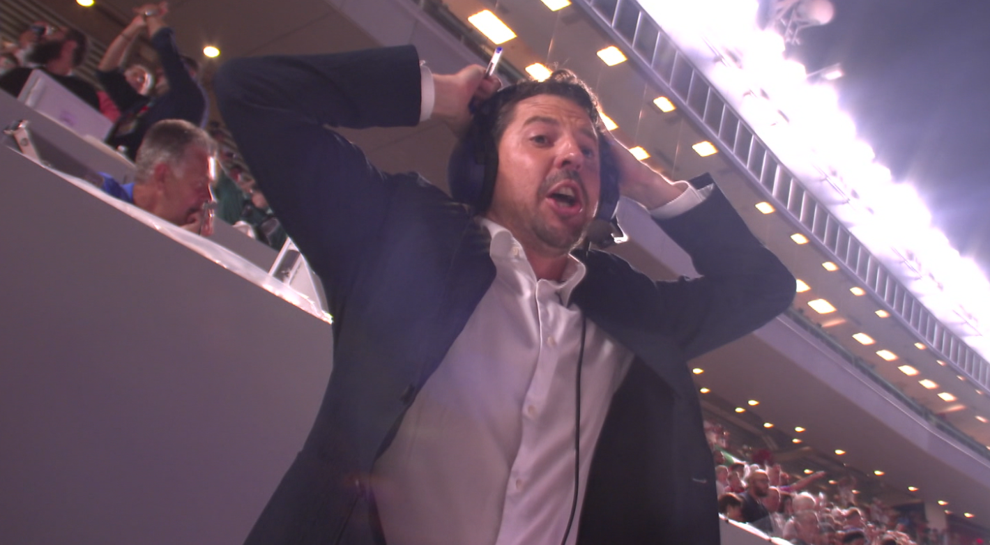 Ein Mann mit Headset hält sich im Stadion überrascht die Hände an den Kopf.