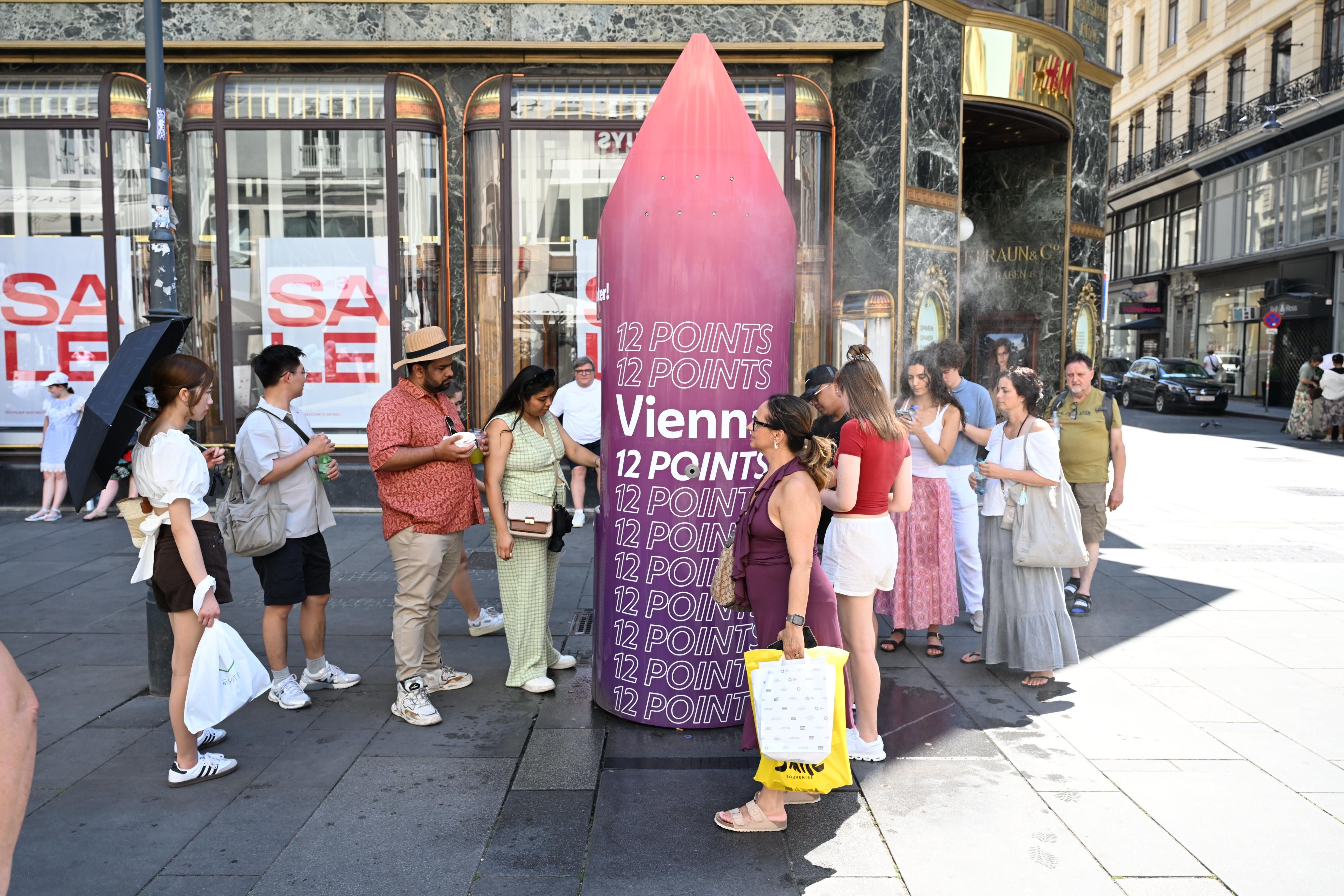 Menschen versammeln sich um einen Sprühnebel-Spender in der Wiener Innenstadt bei Sommerhitze.