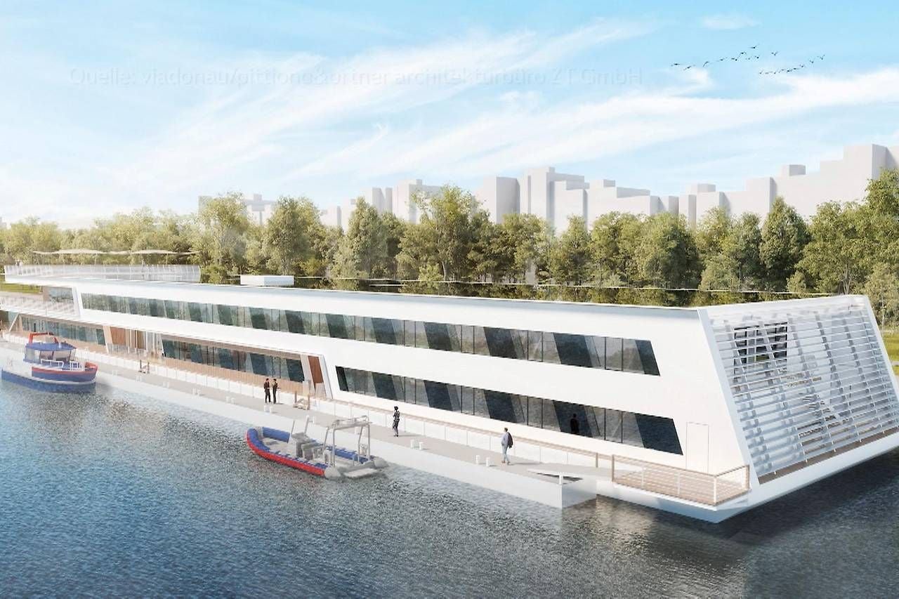 Modernes, schwimmendes Bürogebäude am Ufer mit großen Fenstern und Booten davor.