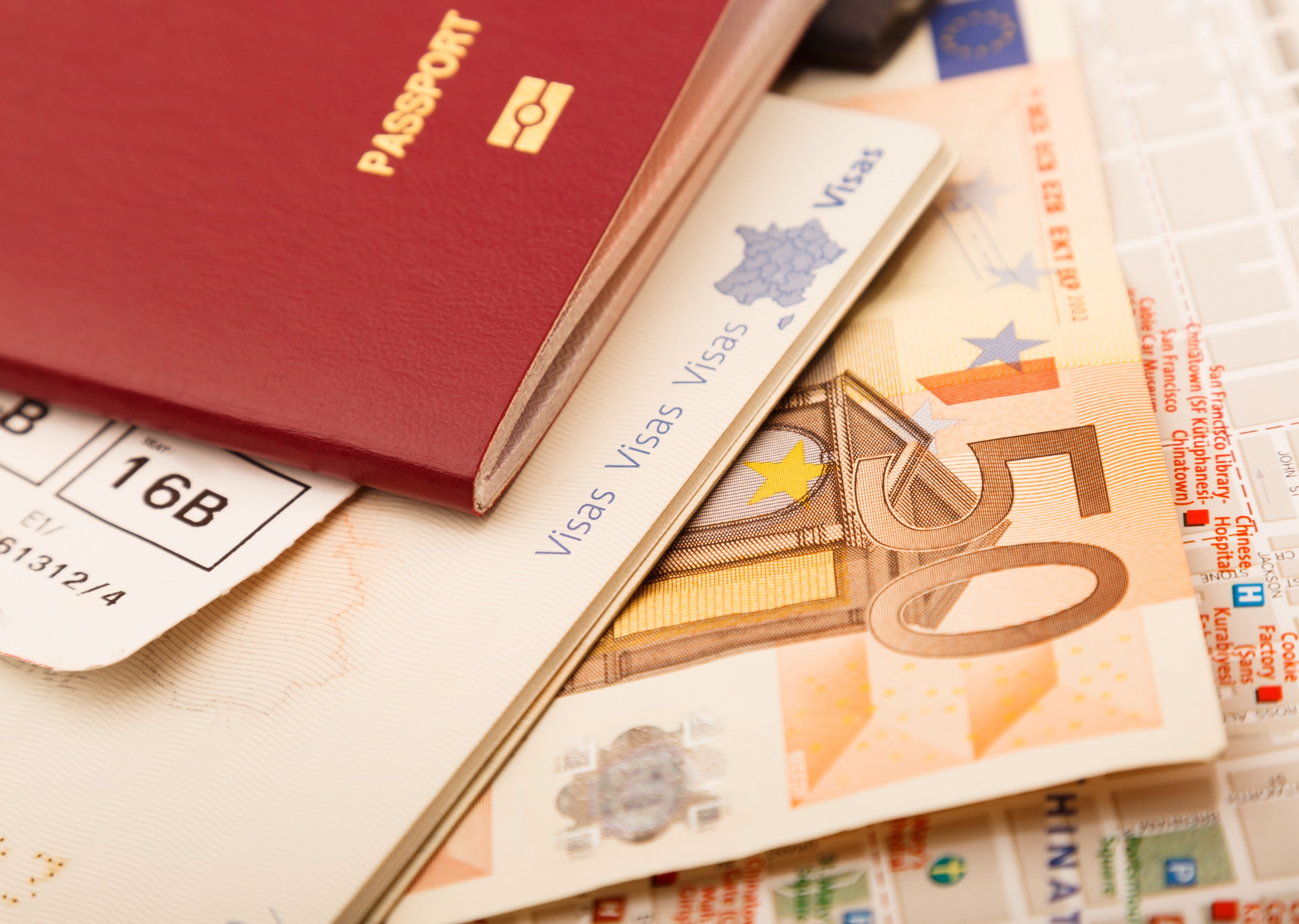 Reisepass, Flugticket, 50-Euro-Schein und Stadtkarte liegen übereinander.