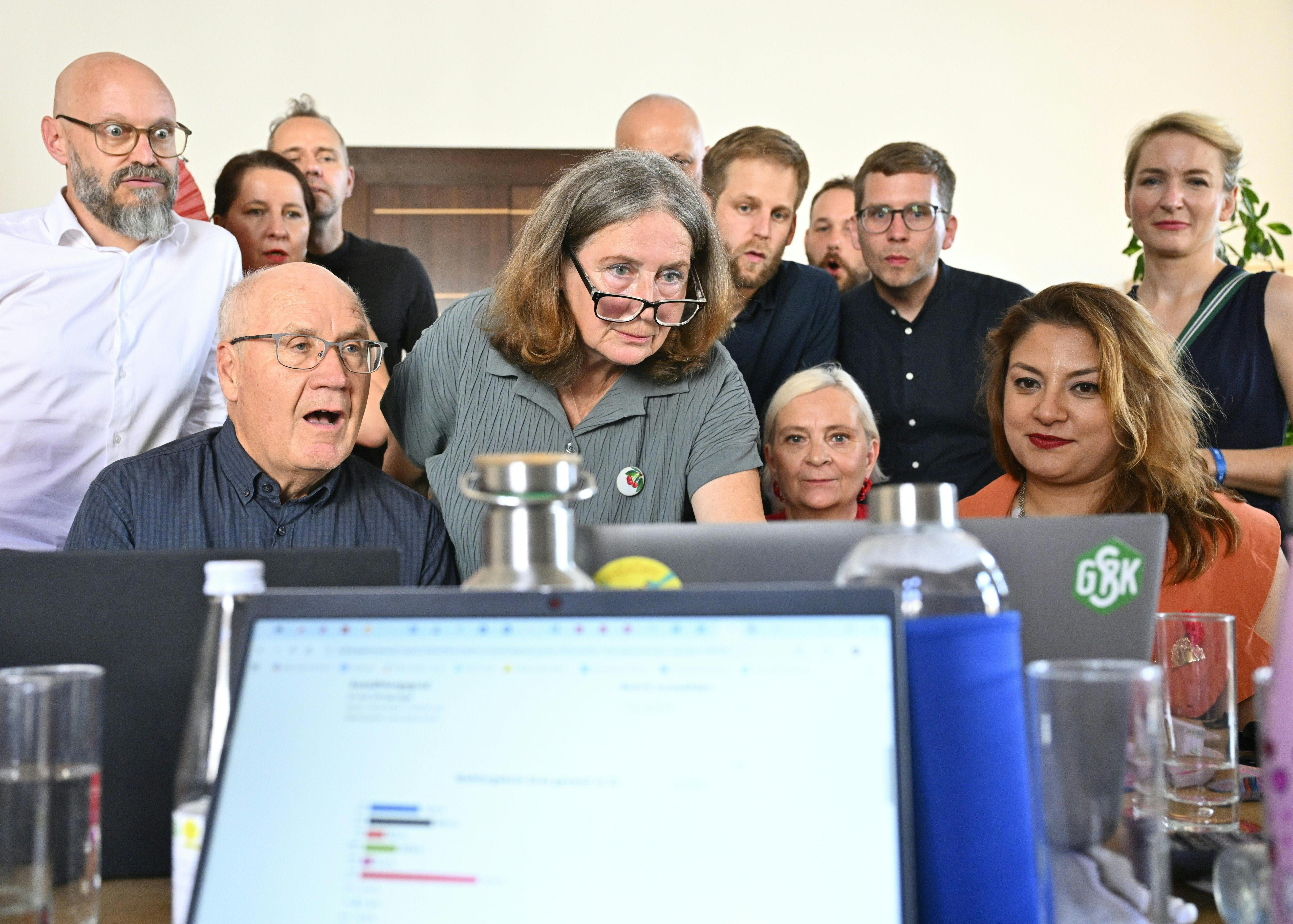 Mehrere Personen verfolgen gespannt die Bekanntgabe des Wahlergebnisses am Laptop in einem Büro.