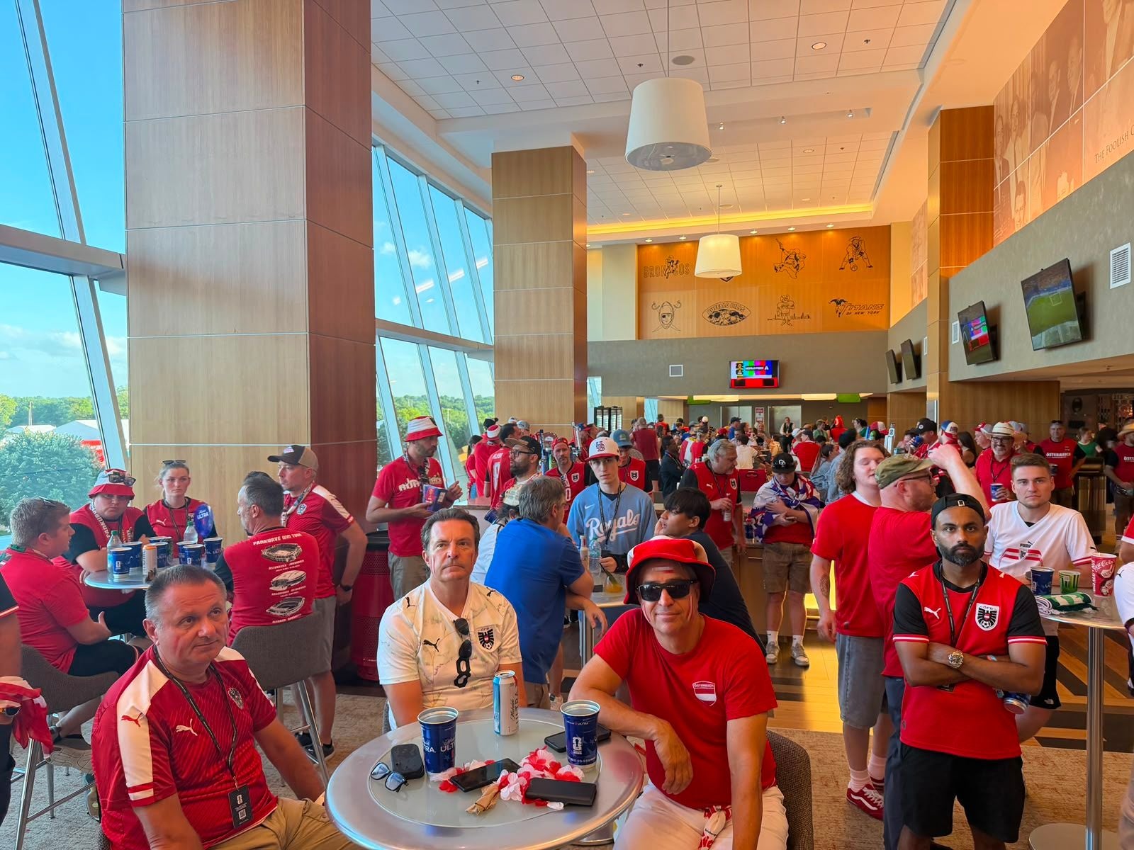 Viele ÖFB-Fans in Rot und Weiß sitzen und stehen in einer modernen Stadionlounge.
