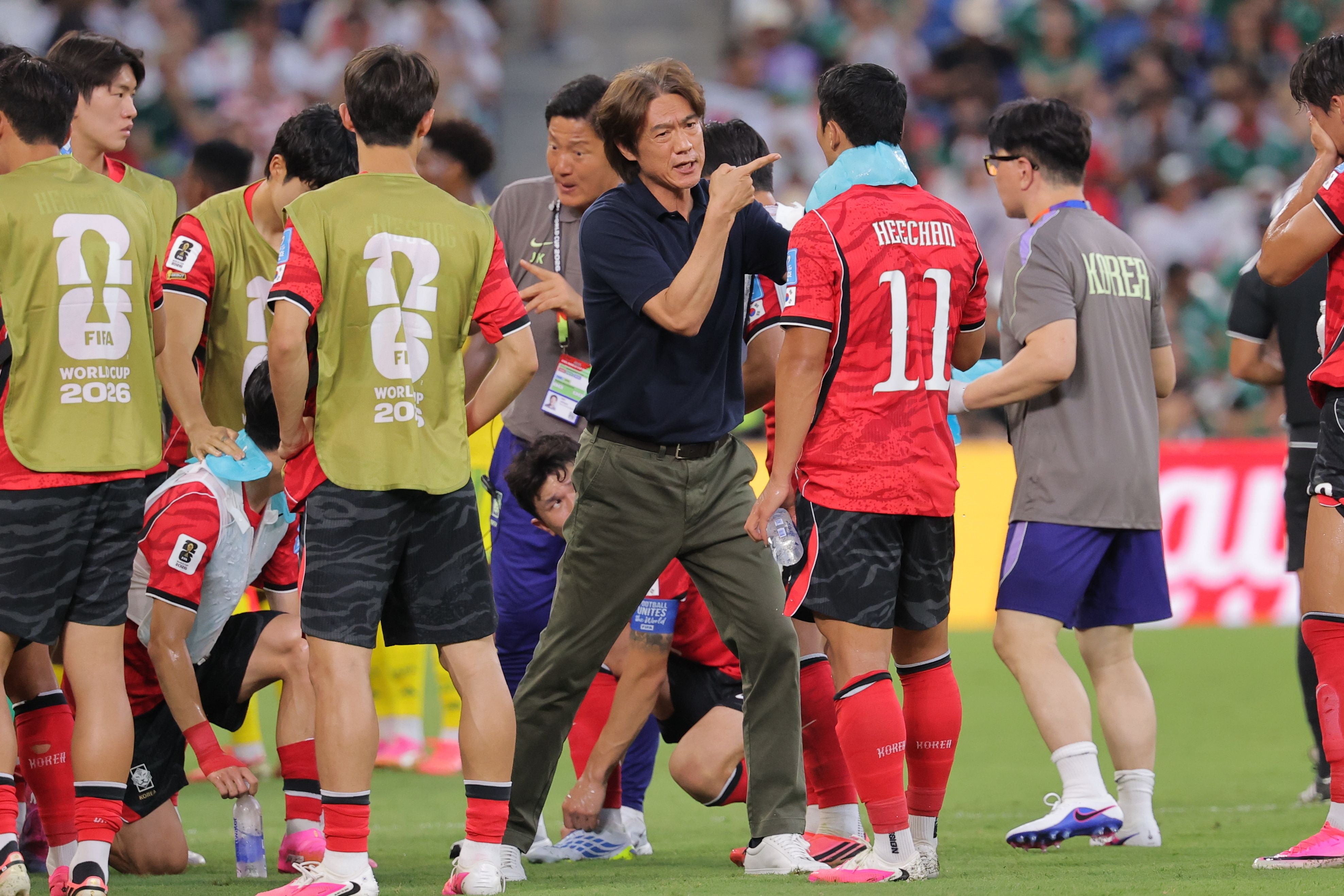 Trainer von Südkorea gibt Fußballspielern während einer Trinkpause Anweisungen.